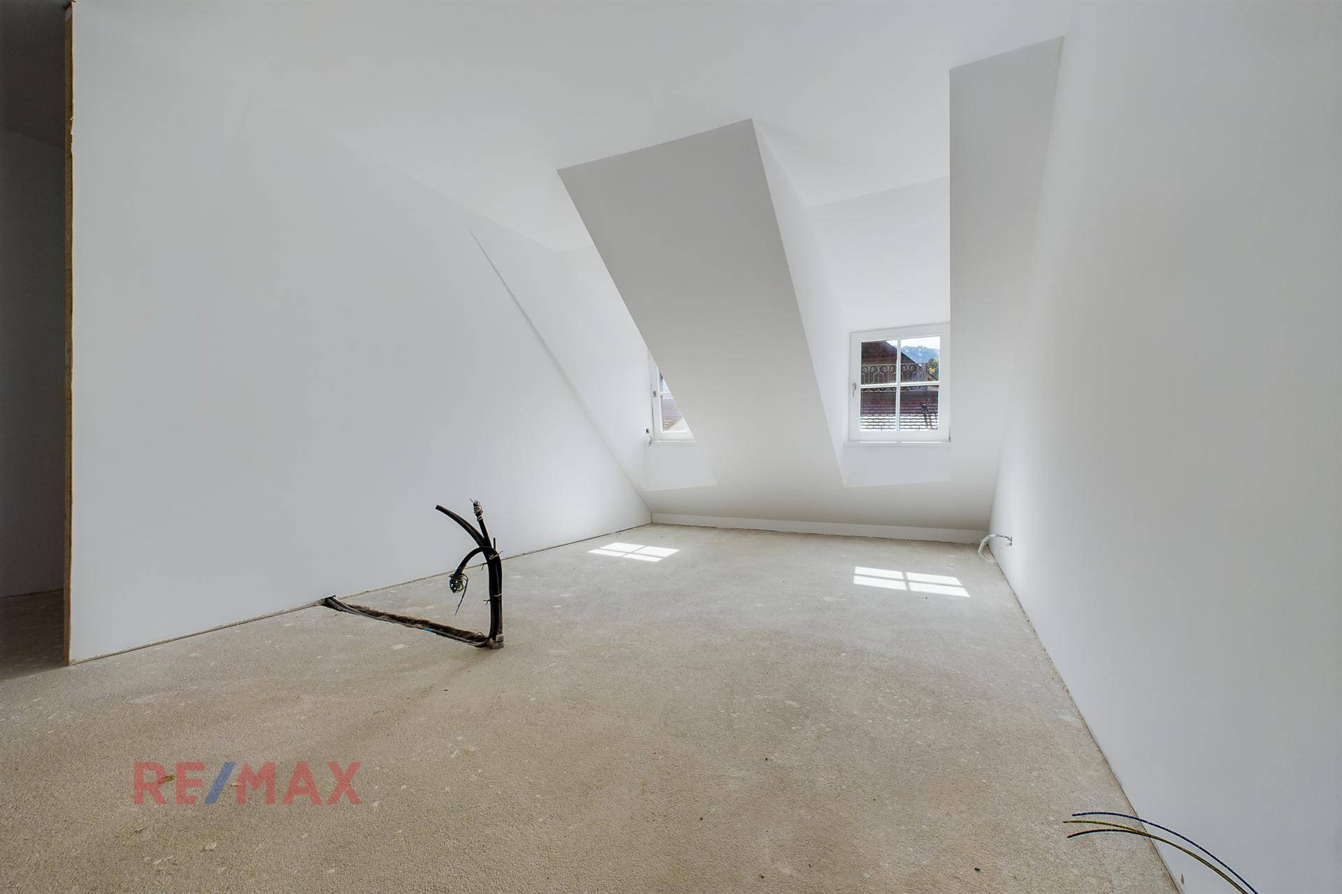 Heller Raum im Dachgeschoss mit schrägen Wänden und kleinen Fenstern, ideal für individuellen Ausbau.