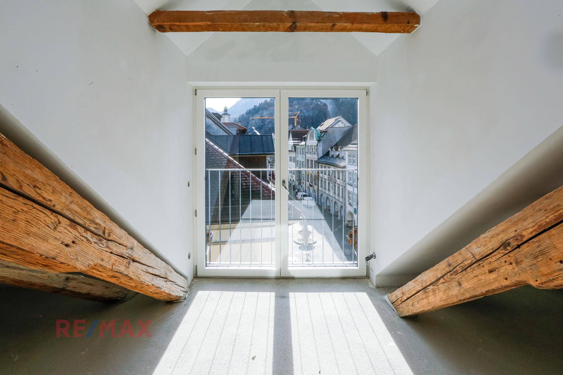 Heller Dachboden mit französischem Balkon und Blick auf die umliegende Stadt und die Berge.