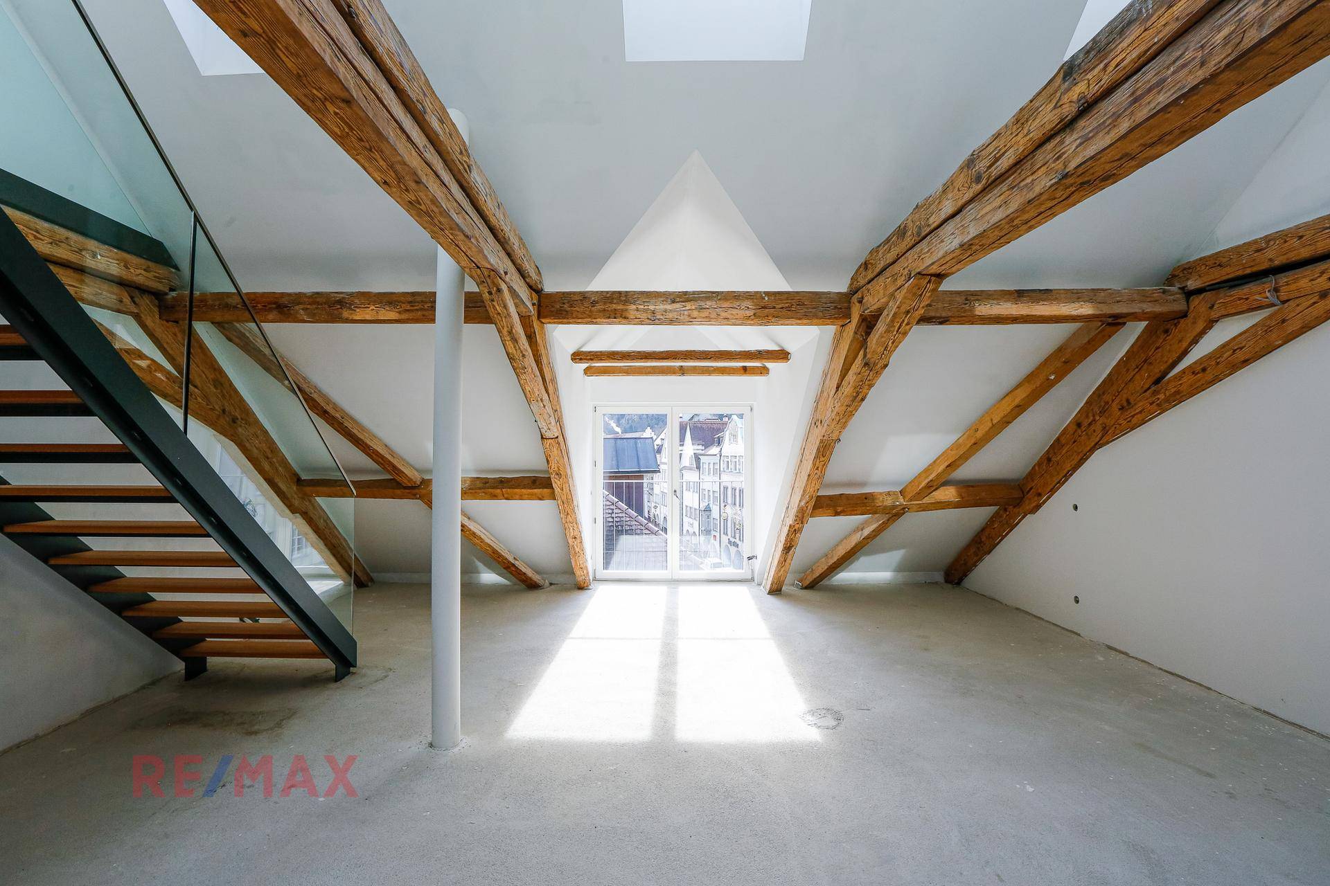 Lichtdurchfluteter Dachboden mit freiliegenden Holzbalken und einer modernen Treppe, die nach oben führt.