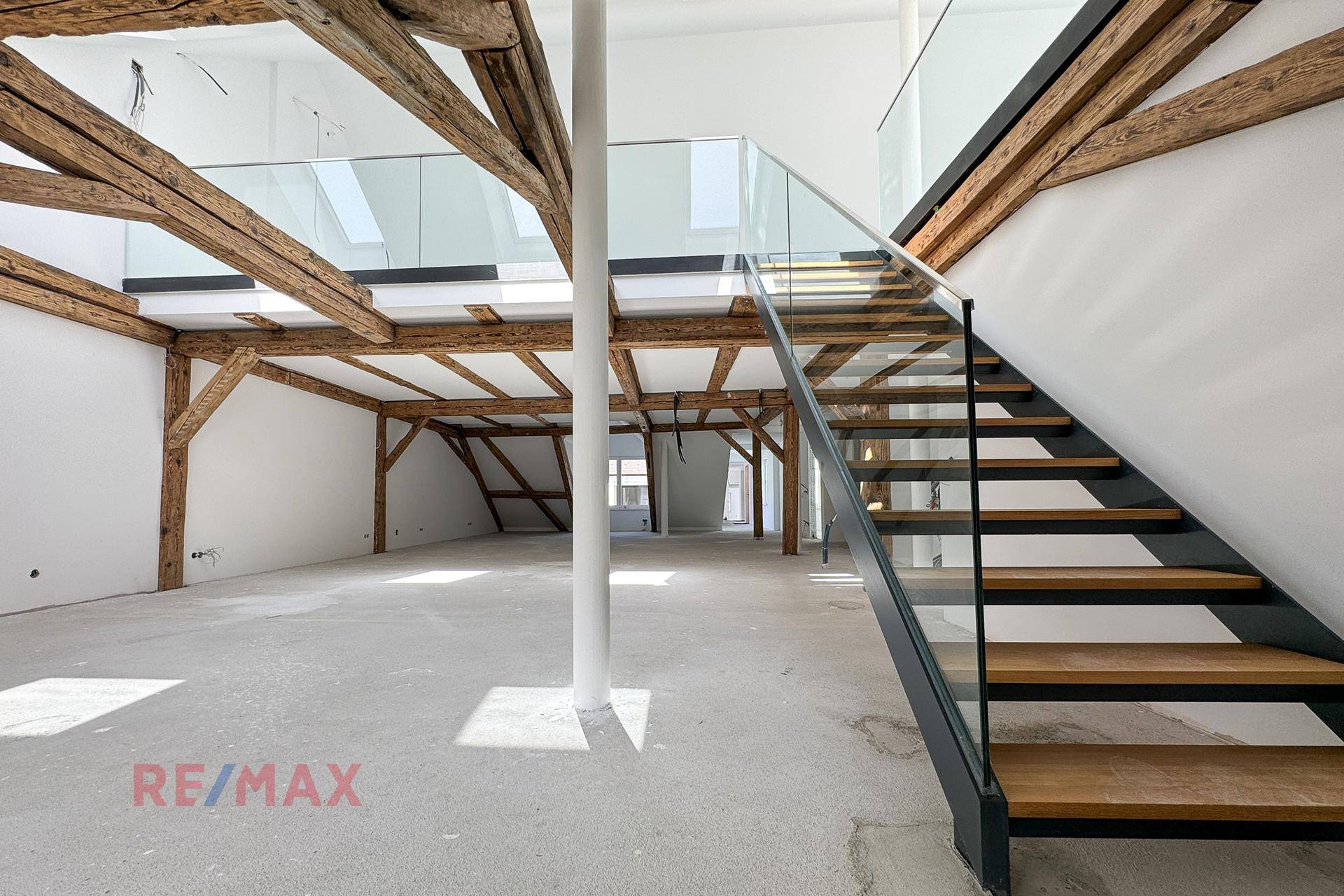 Geräumiger Dachboden mit sichtbaren Holzbalken und einer eleganten Treppe, die viel Potenzial bietet.