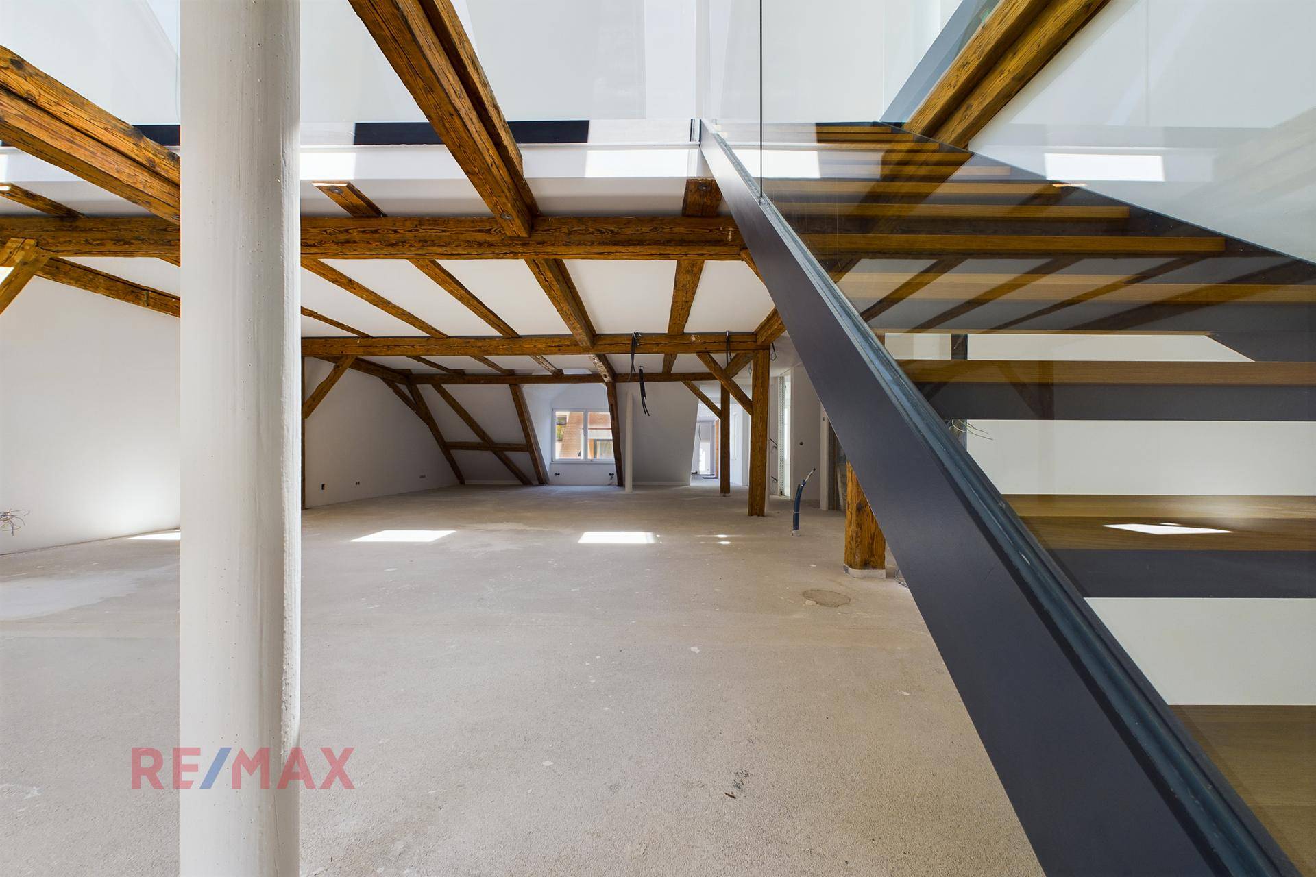 Offener Dachbodenbereich mit moderner Treppe und freiliegenden Holzbalken, der auf den Ausbau wartet.