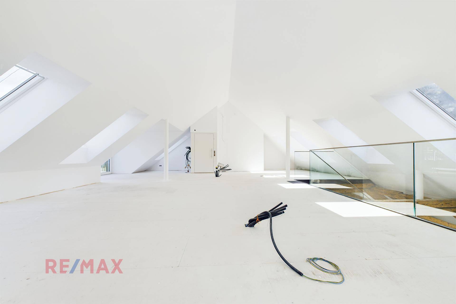 Heller und offener Dachbodenbereich mit schrägen Wänden und Dachfenstern, ideal für ein Studio oder Büro.