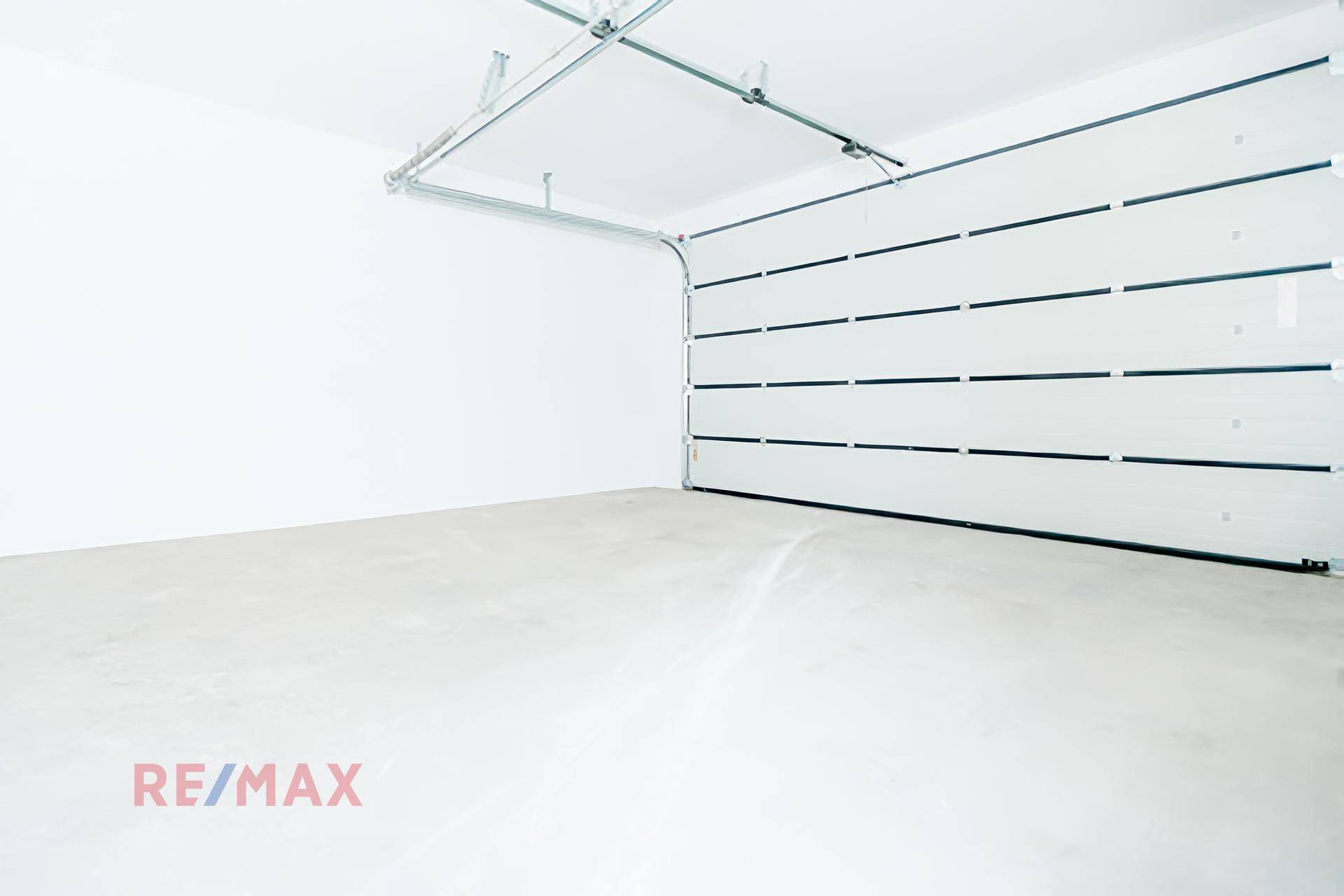 Geräumige, leere Garage mit einem modernen weißen Sektionaltor und glattem Betonboden.