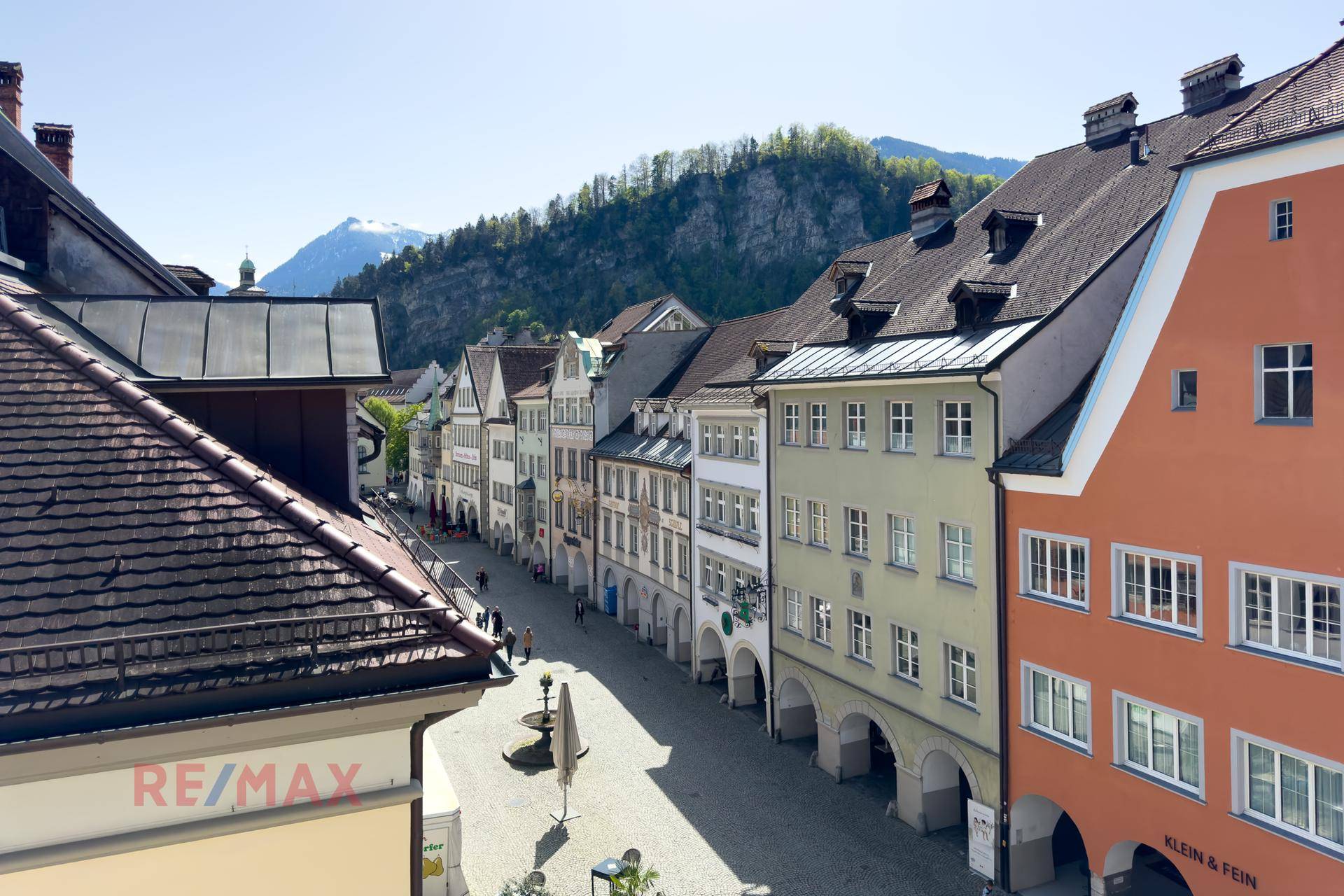 Blick über eine historische Gasse mit traditionellen Gebäuden und Bergen im Hintergrund.