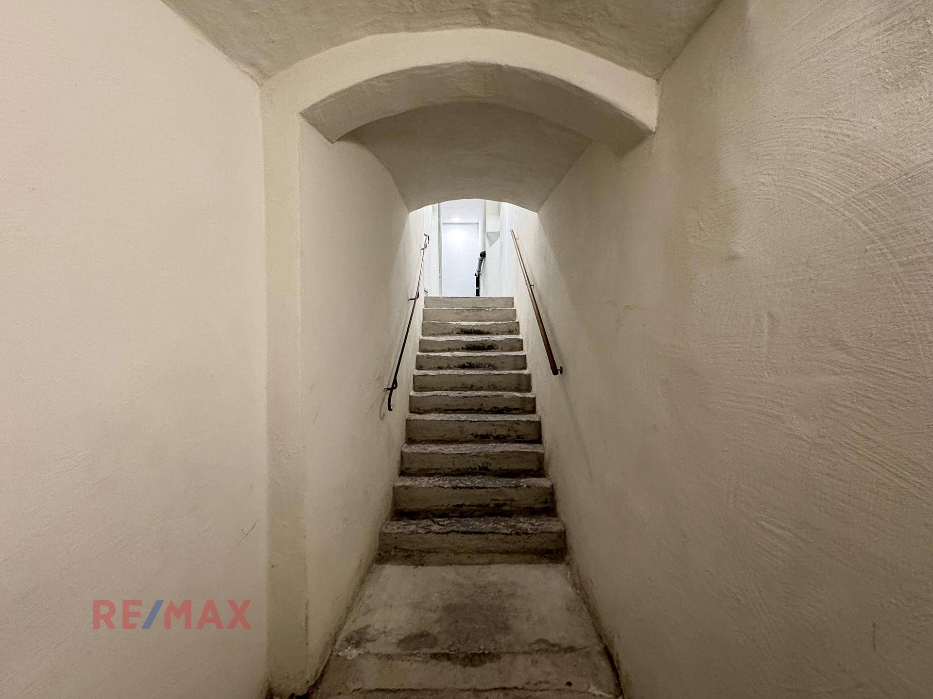 Historisches Treppenhaus mit Steinstufen und einer beeindruckenden Gewölbedecke, die nach oben führt.