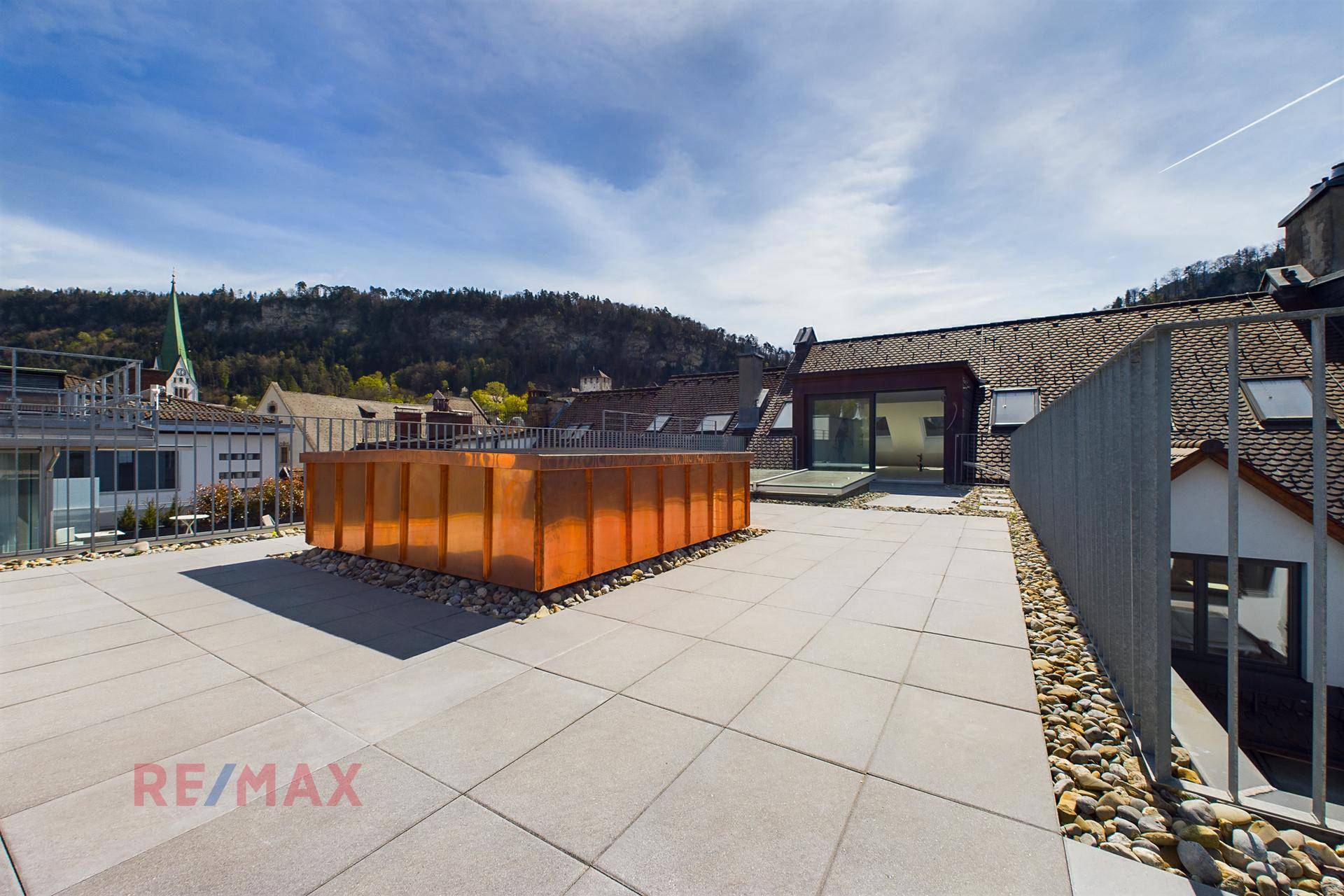 Weitläufige Dachterrasse mit modernem Pflanzgefäß und Panoramablick über die Stadt und Landschaft.