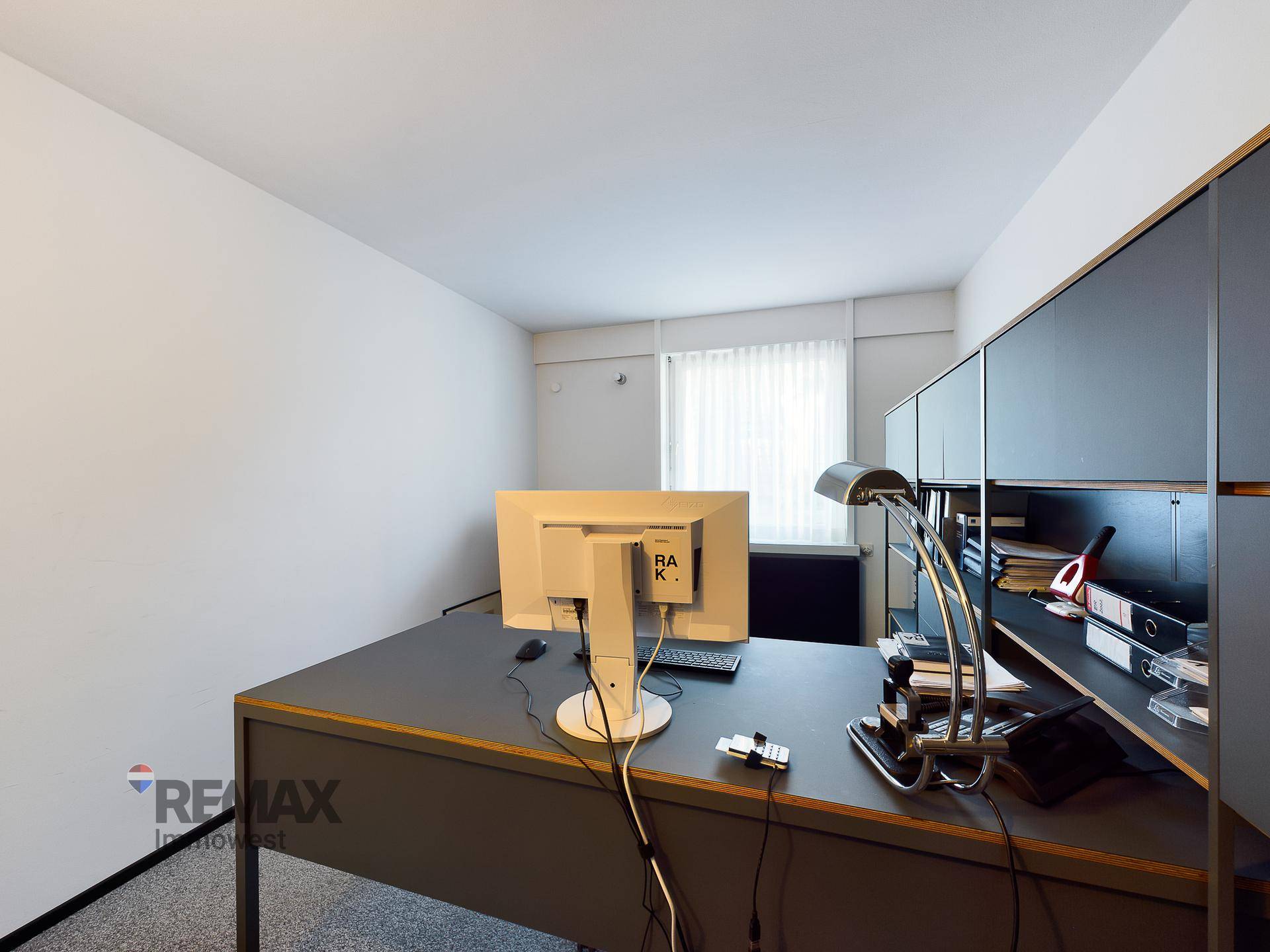 Detailansicht eines modernen Büros mit Schreibtisch, Monitor und integrierten Ablagesystemen.