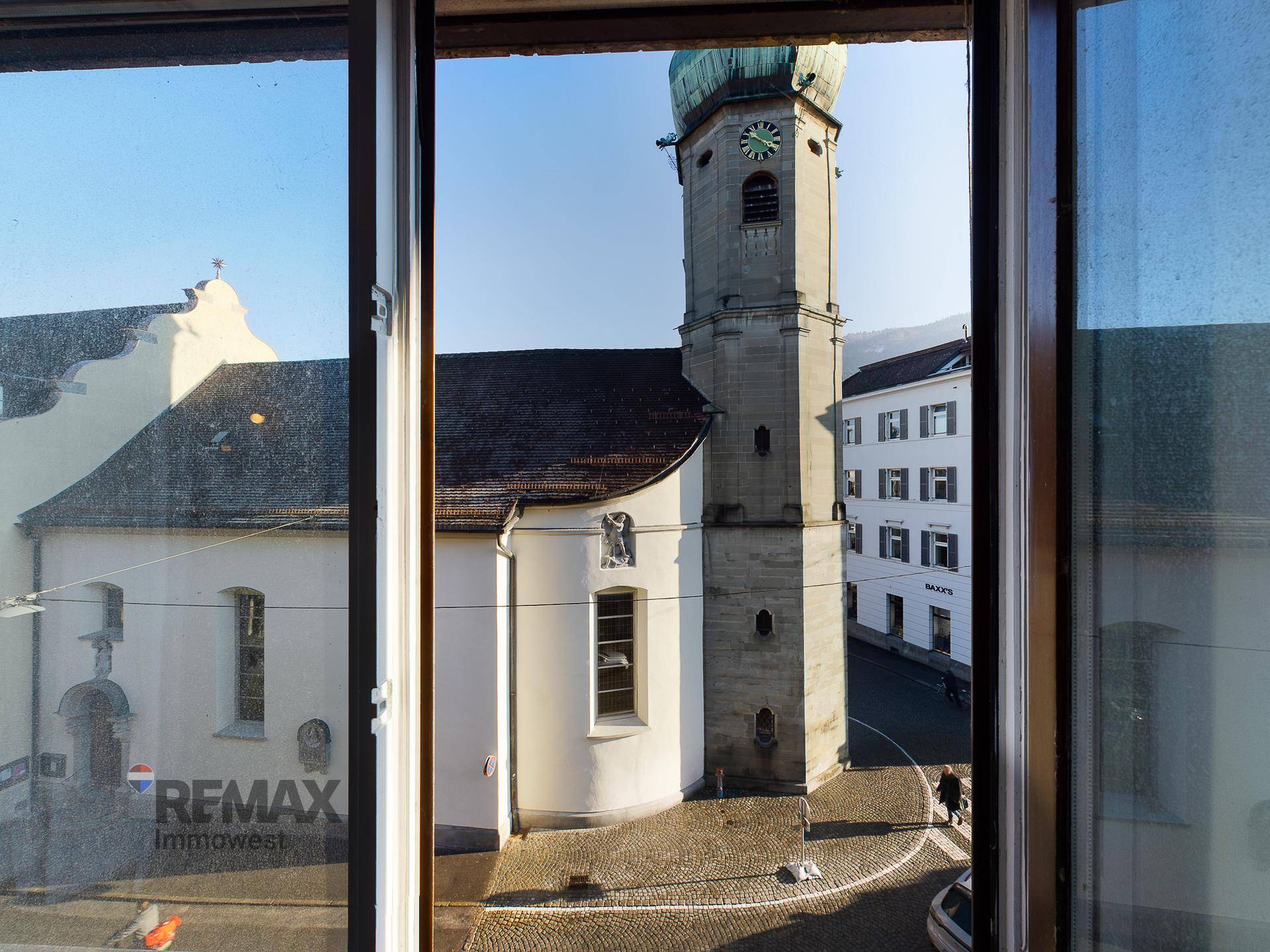 Blick aus dem Fenster auf eine historische Kirche und die umliegende Stadtarchitektur.