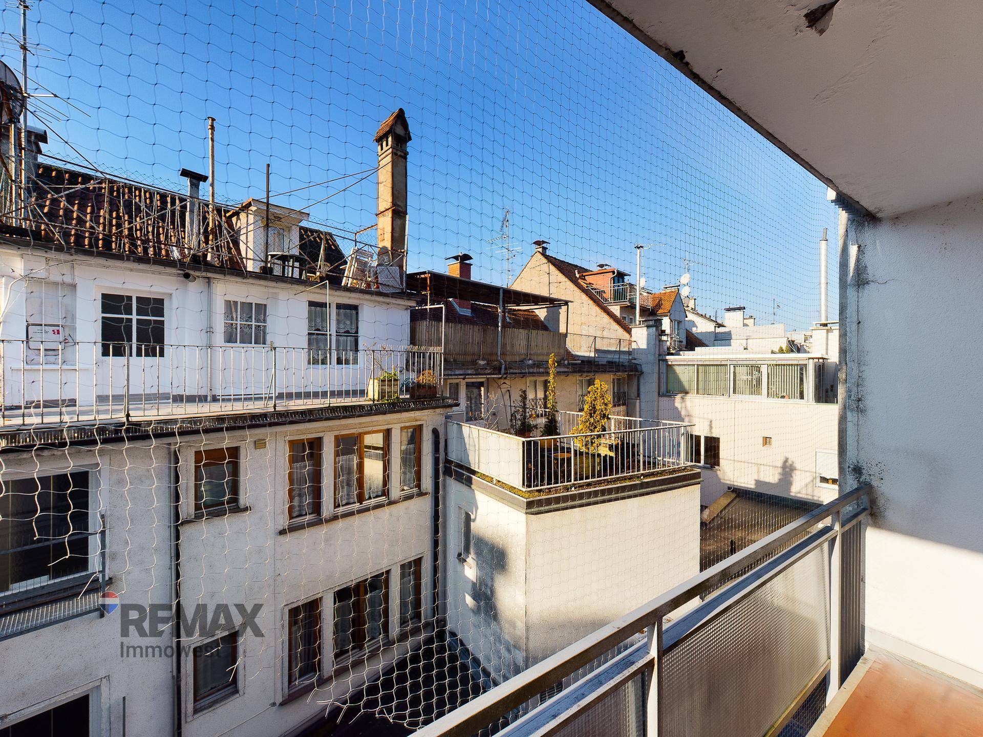 Balkon mit Blick auf die Nachbargebäude und eine Dachterrasse im städtischen Umfeld.