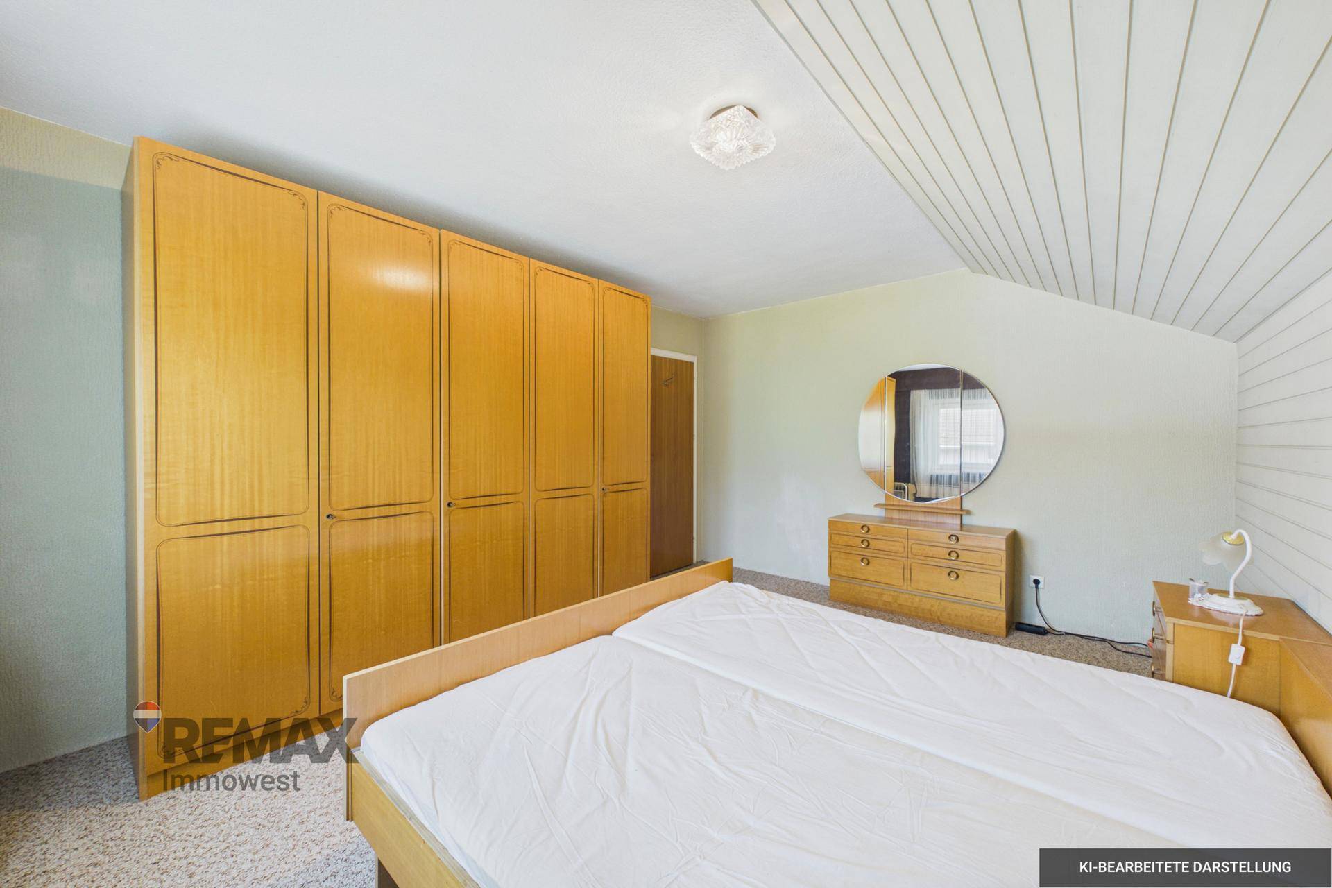 Geräumiges Dachschlafzimmer mit großem Holzschrank, Spiegel und schrägen Decken.