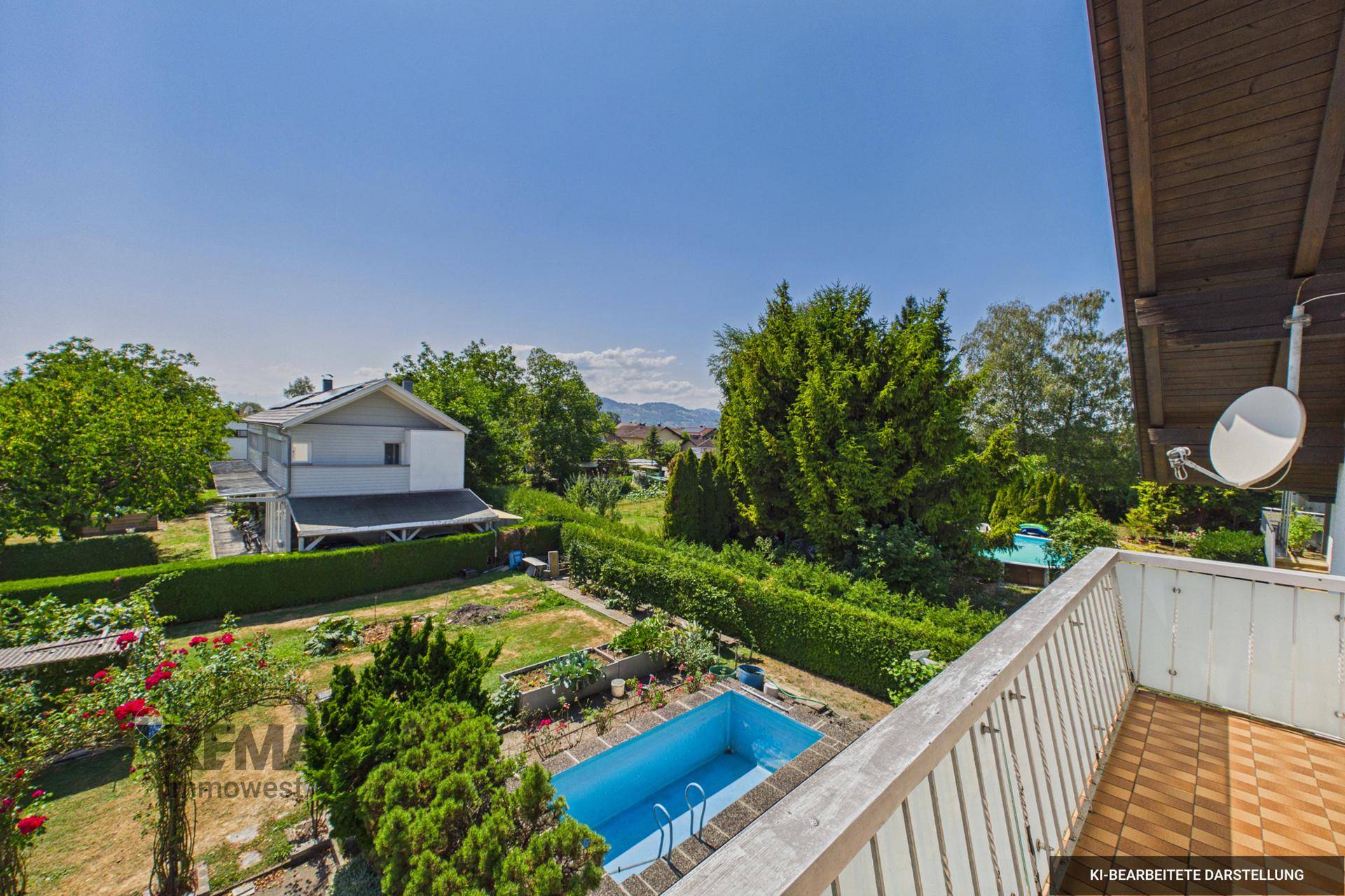 Blick vom Balkon auf den Garten mit Pool und umliegende Häuser unter blauem Himmel.