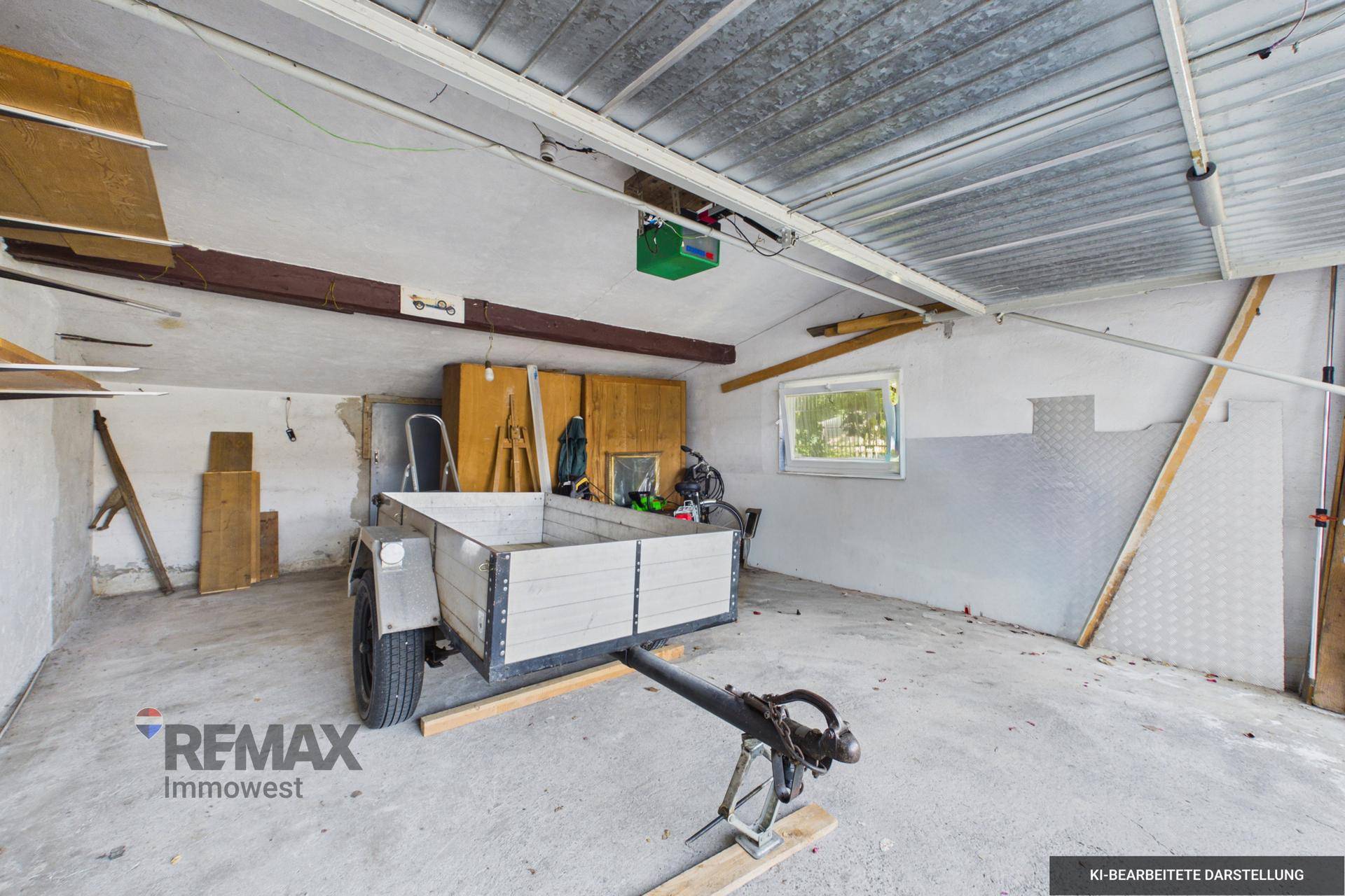Geräumige Garage mit Betonboden, einem Anhänger und einem kleinen Fenster.