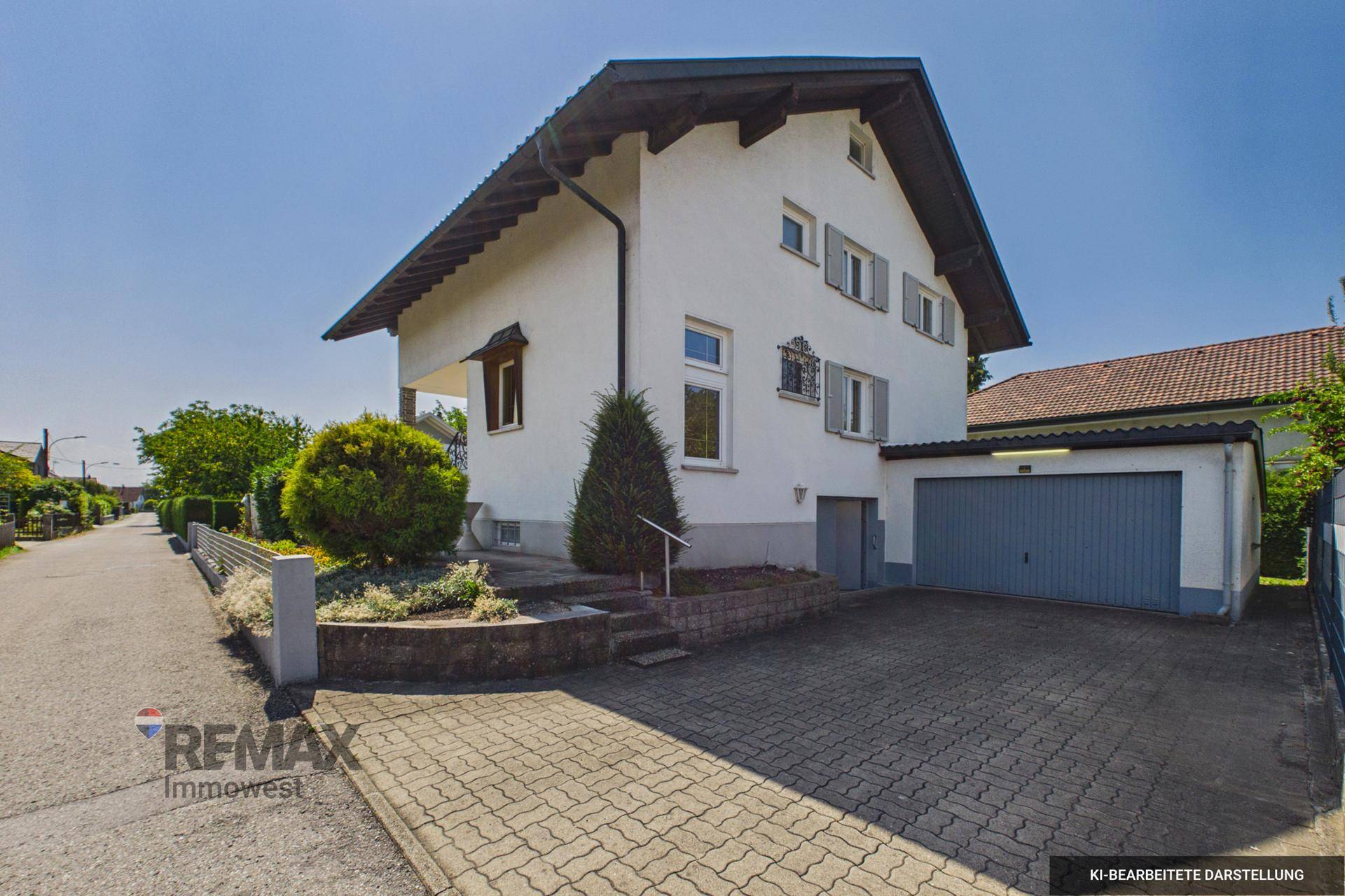 Ansicht des Hauses von der Straße mit Garage, gepflasterter Einfahrt und Vorgarten.