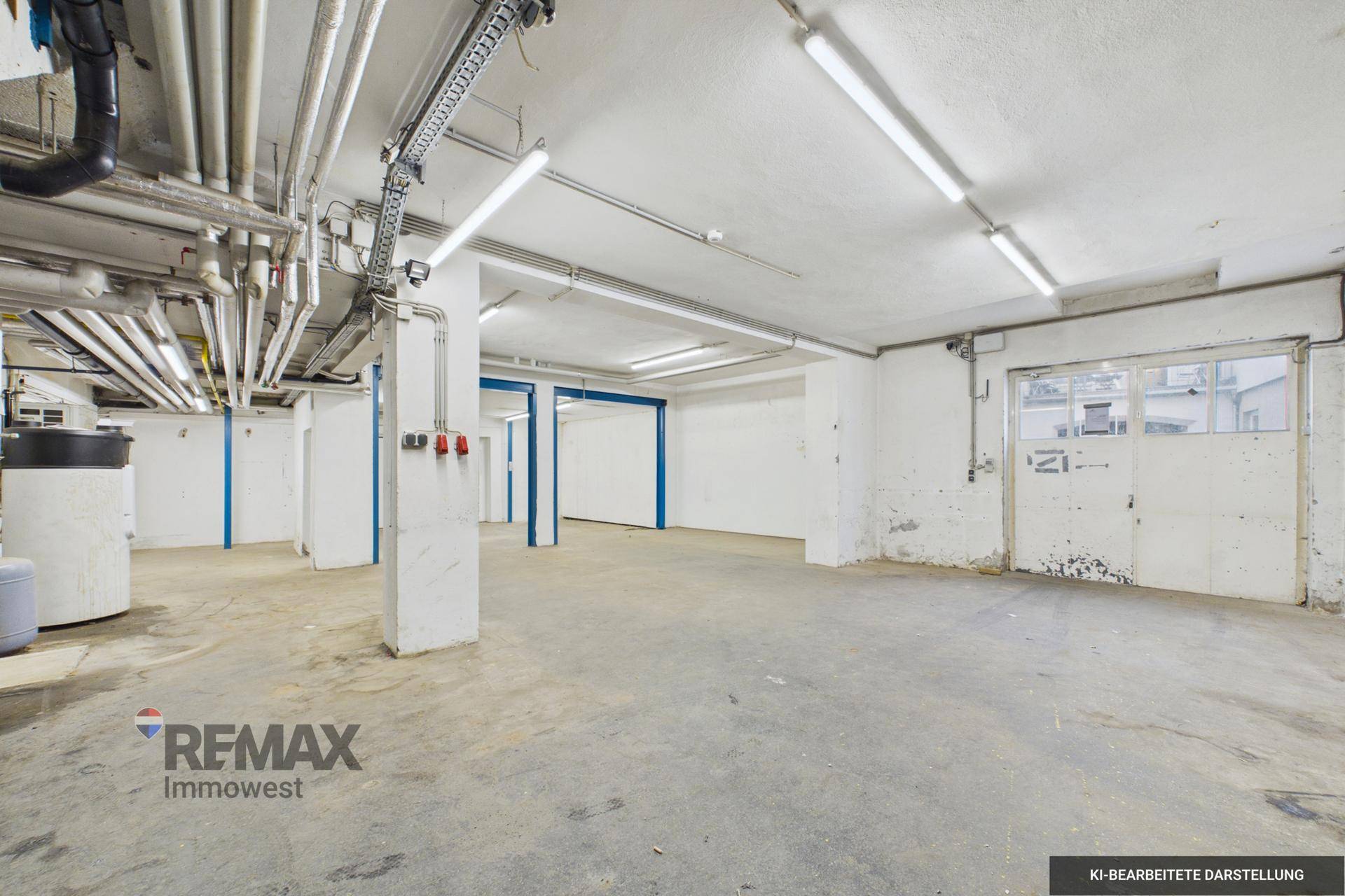 Großer Kellerraum mit Betonboden, sichtbaren Installationen und einer breiten Tür, gut beleuchtet.