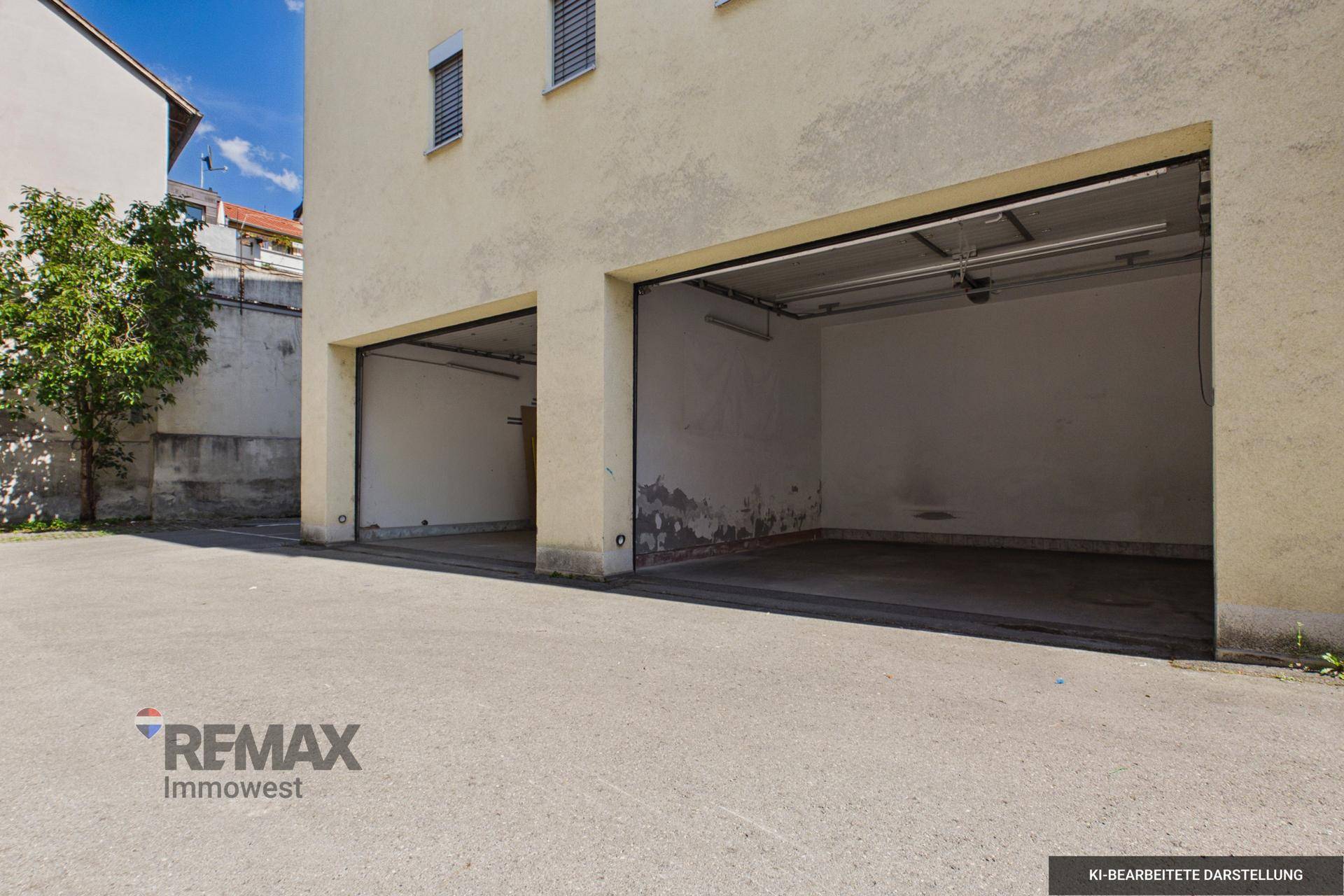Zwei offene Garagenboxen an einem Gebäude mit asphaltierter Zufahrt und hellem Putz.