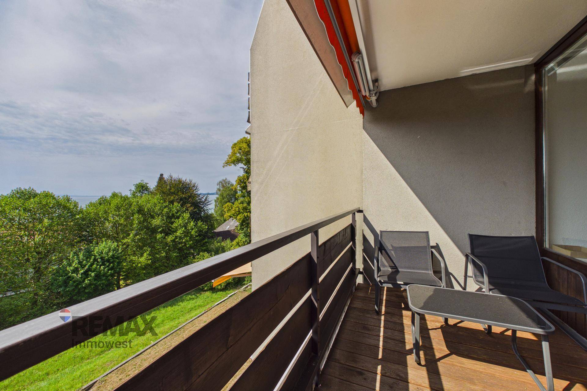 Balkon mit Holzboden und Metallgeländer, bietet einen weiten Blick auf den See und die Umgebung.