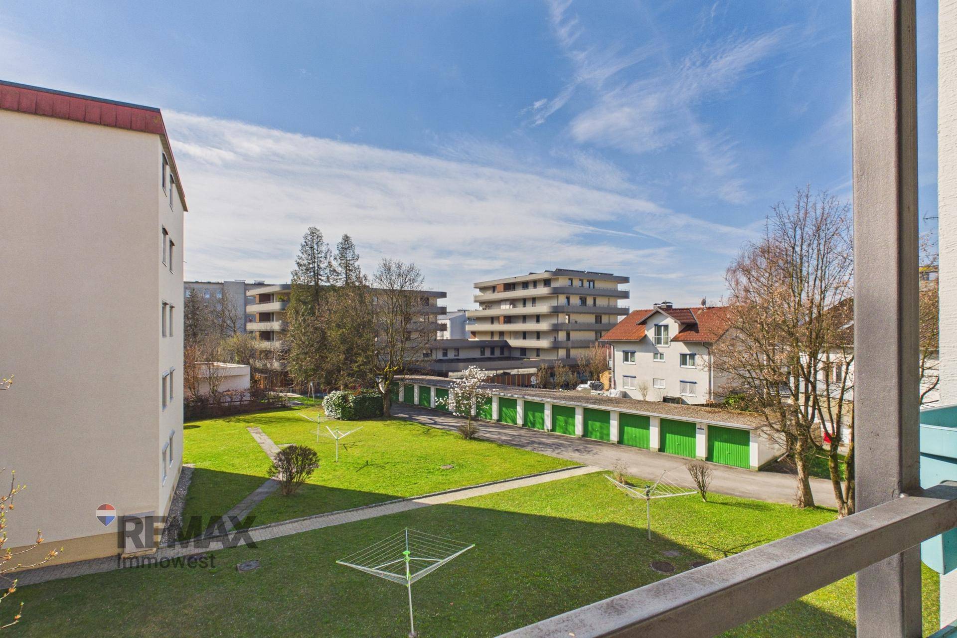 Weitläufiger Blick vom Balkon über die grüne Wohnanlage mit Garagen und umliegenden Gebäuden.
