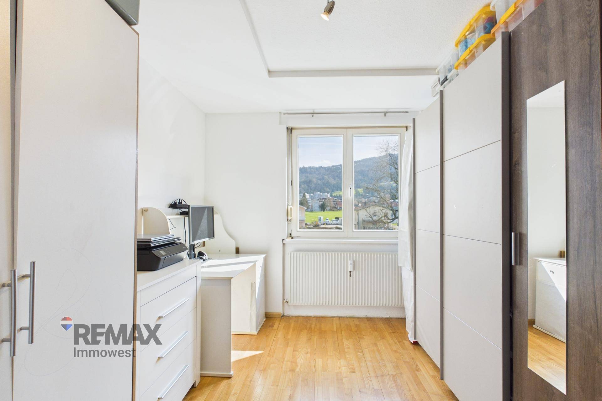 Helles Schlafzimmer mit Fenster, Schreibtisch und Blick ins Grüne.