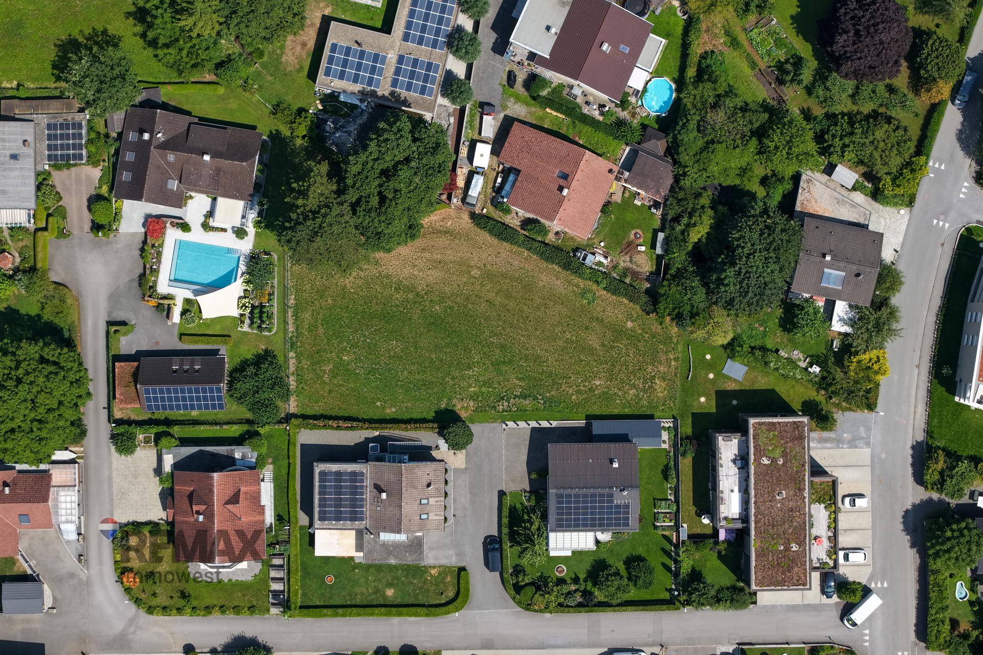 Luftaufnahme des Grundstücks und der angrenzenden Wohnsiedlung, viele Dächer mit Solaranlagen und Pools.
