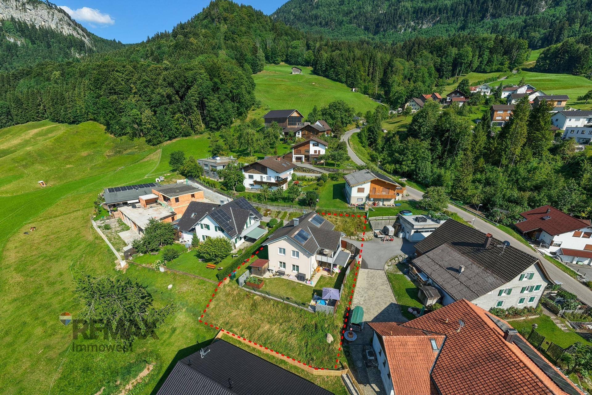 Luftaufnahme des Einfamilienhauses mit Grundstücksgrenzen und umliegender grüner Landschaft.