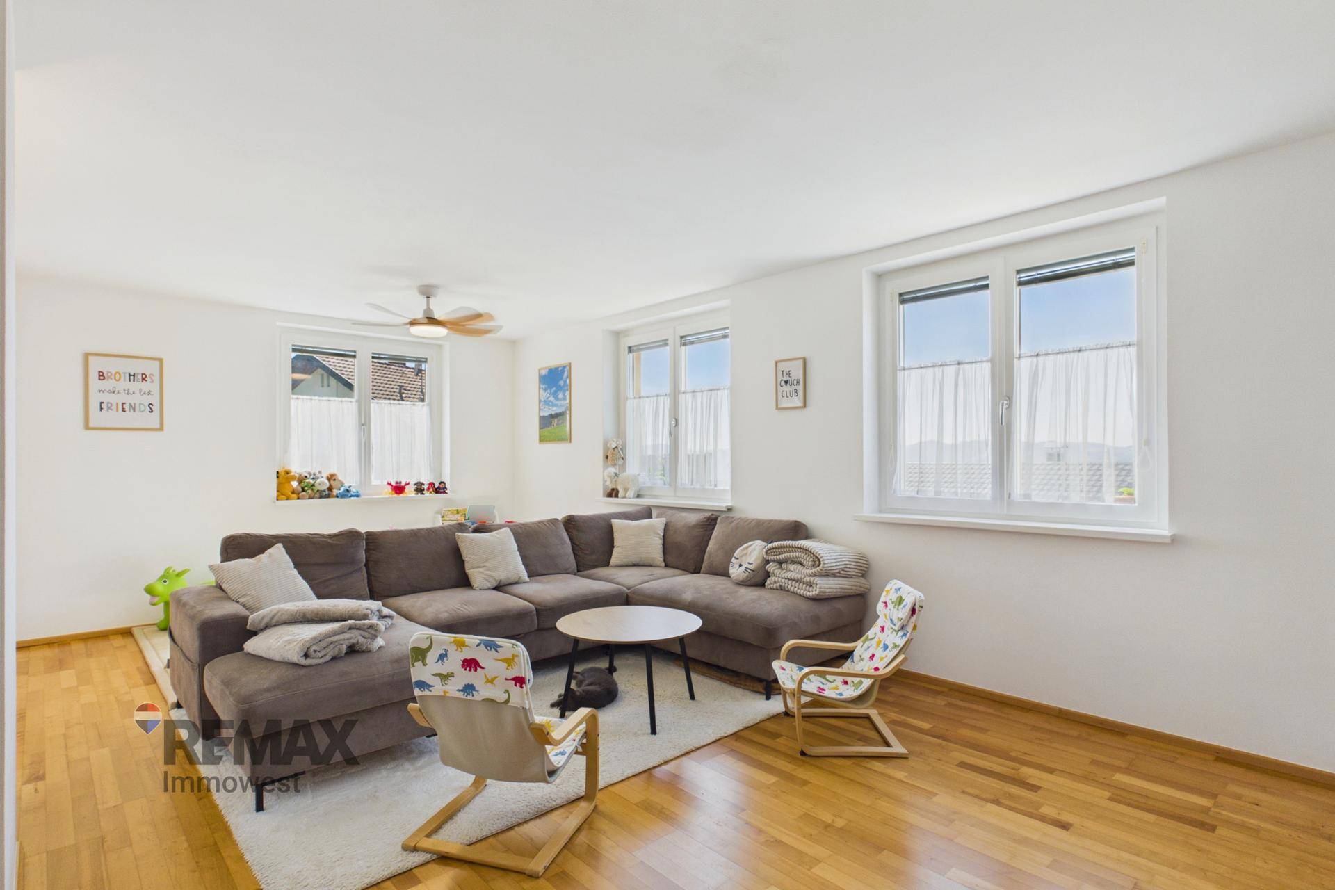 Geräumiges Wohnzimmer mit großem Ecksofa, Holzparkett und Deckenventilator.