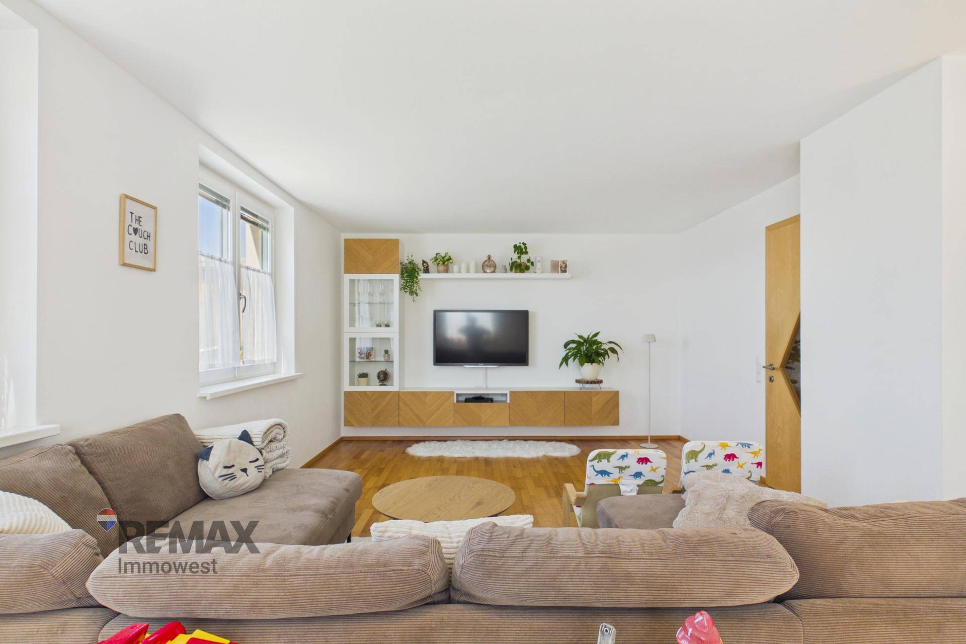 Modern eingerichtetes Wohnzimmer mit großem Sofa, TV-Möbeln und hellem Parkettboden.