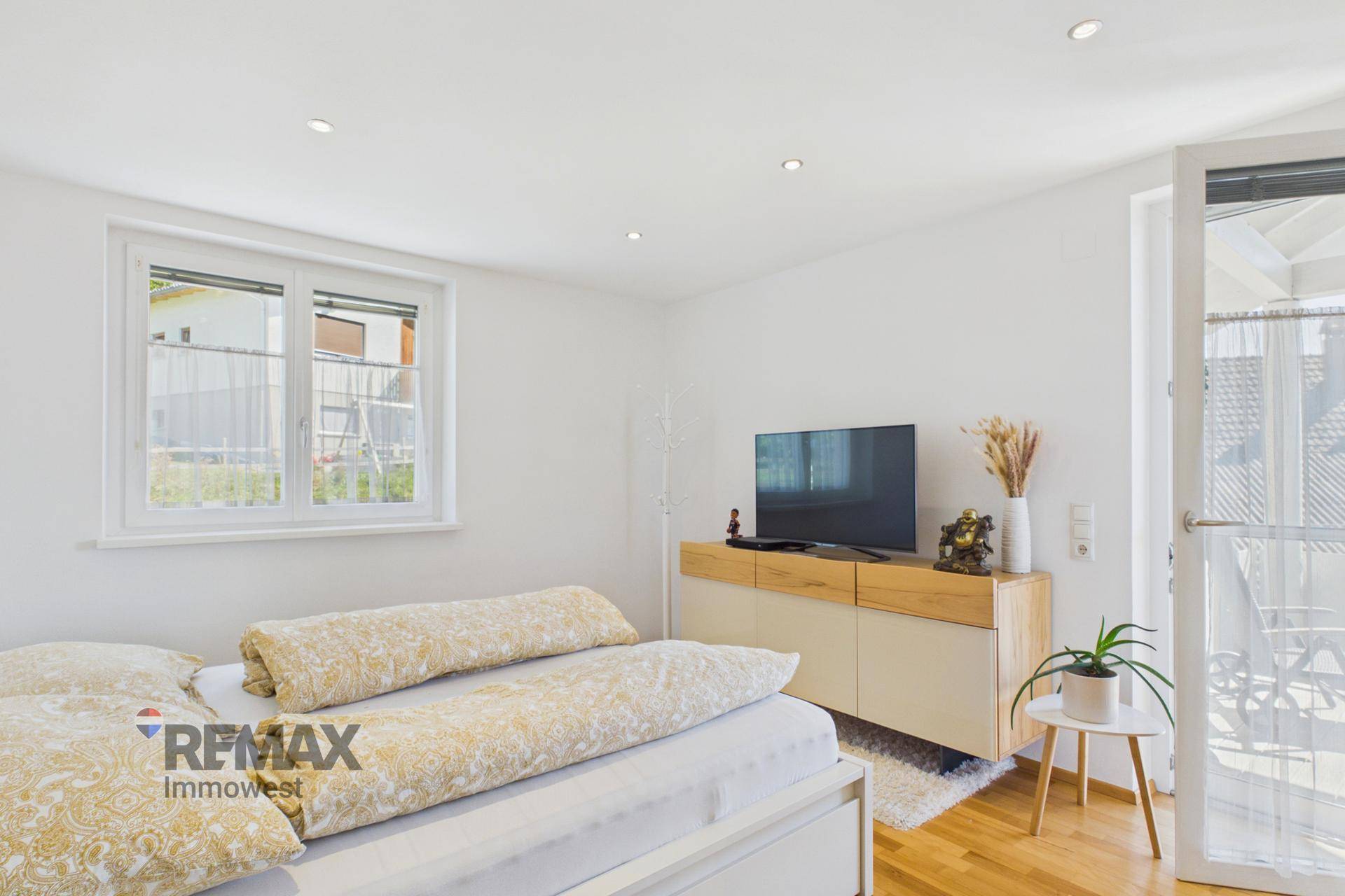 Helles Schlafzimmer mit Doppelbett, Holzparkett und Zugang zum Balkon.