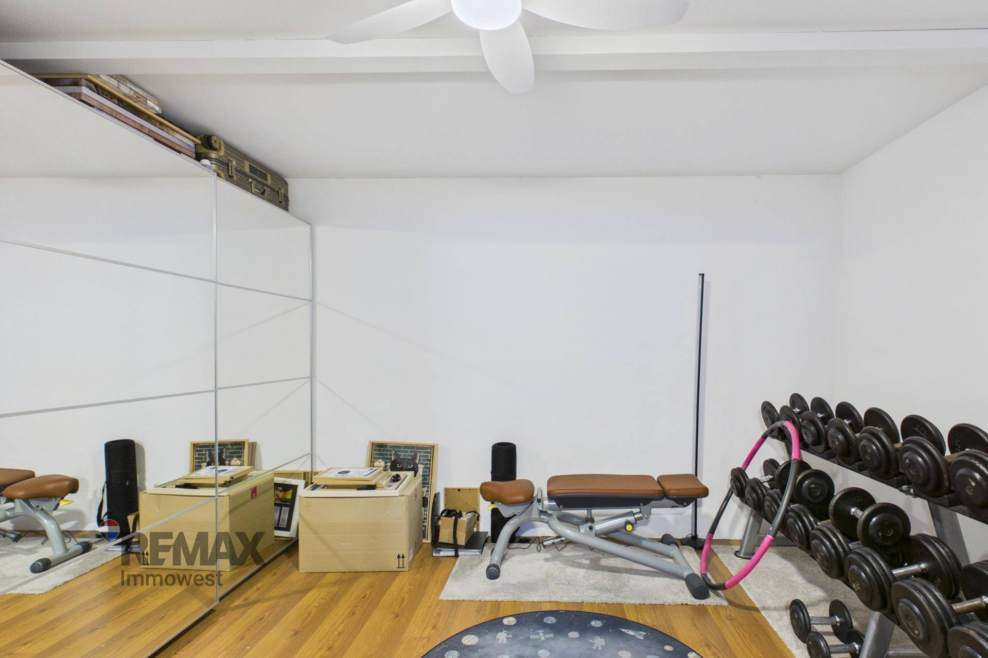 Fitnessraum mit Spiegelfront, Hanteln und Trainingsbank für das Heimtraining.
