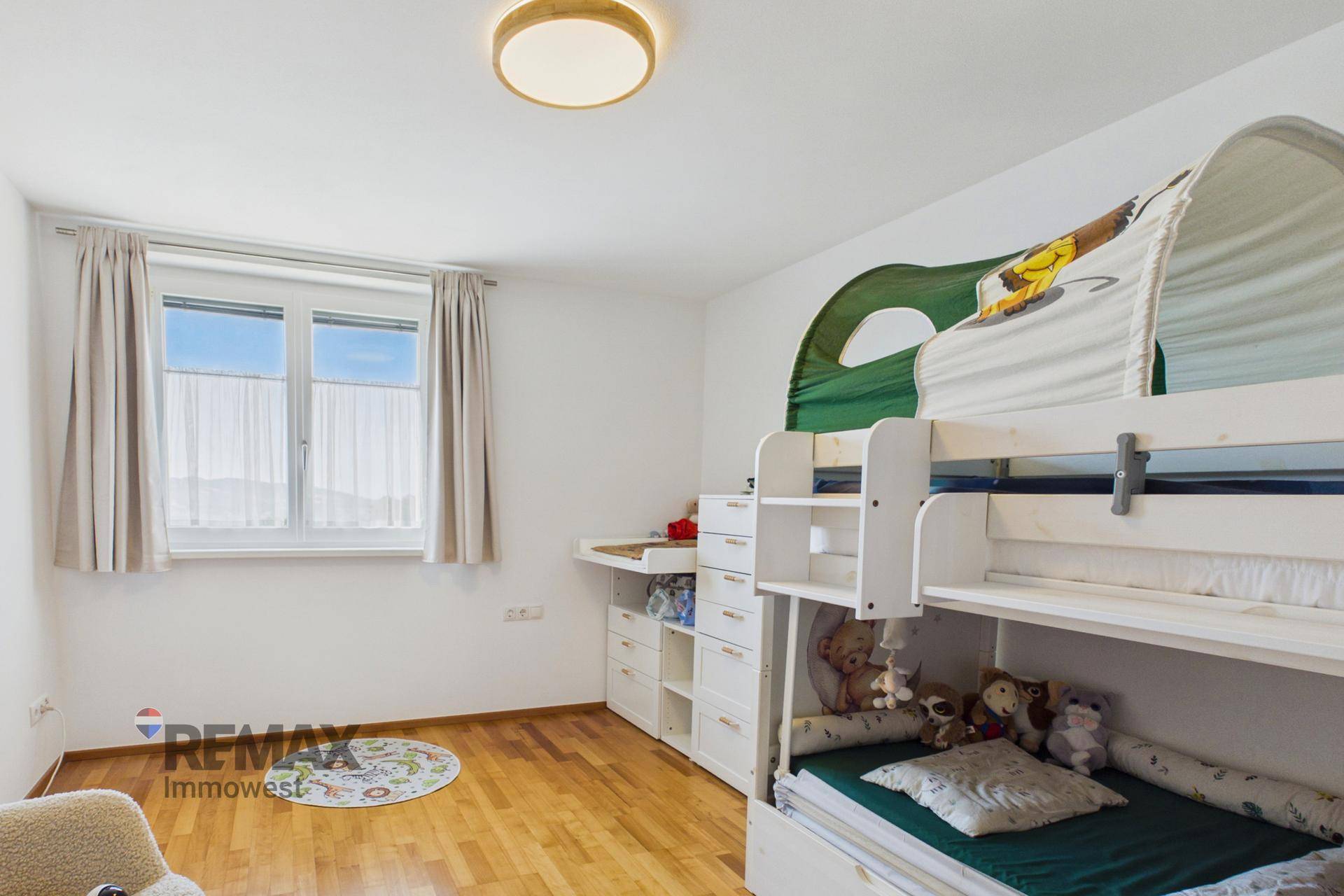 Kinderzimmer mit Etagenbett, Holzparkett und hellem Fenster für viel Tageslicht.