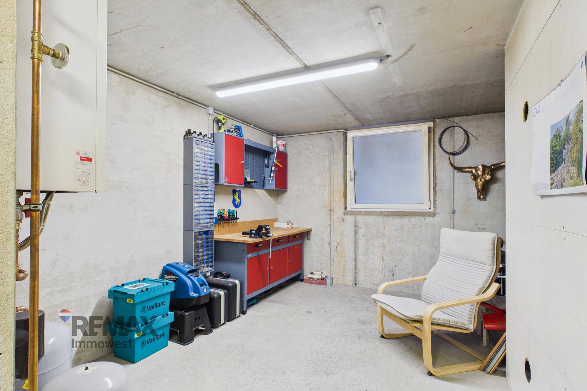 Werkstatt im Keller mit Werkbank, Regalen und einem kleinen Fenster für Tageslicht.