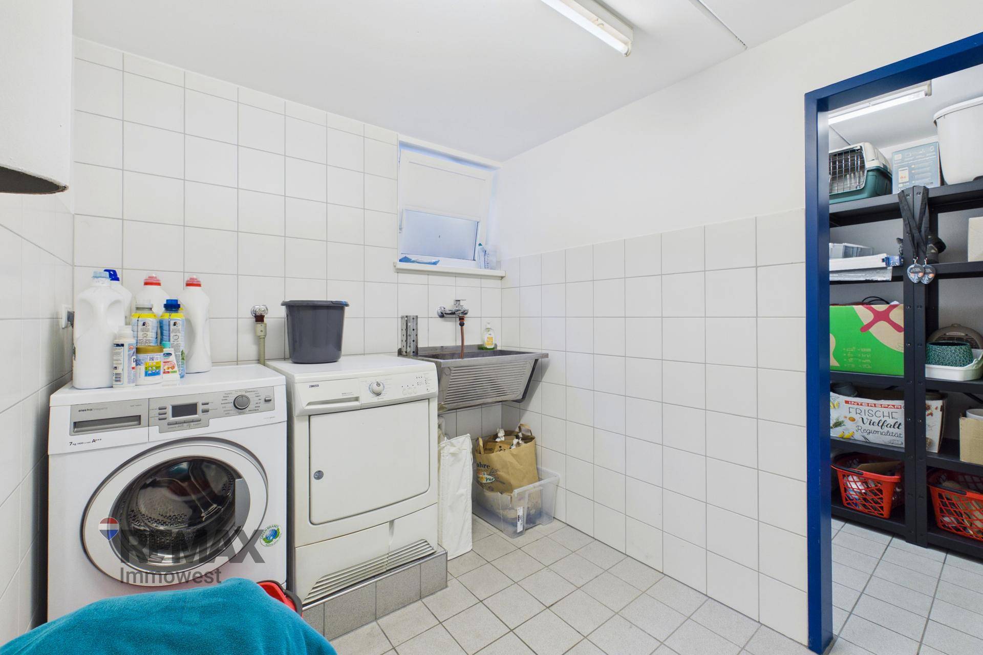 Praktischer Waschraum im Keller mit Waschmaschine, Trockner und Waschbecken.