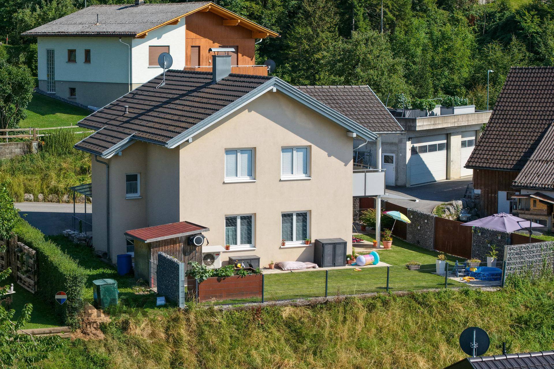 Einfamilienhaus mit gepflegtem Garten, Rasenfläche und Sitzgelegenheiten im Freien.