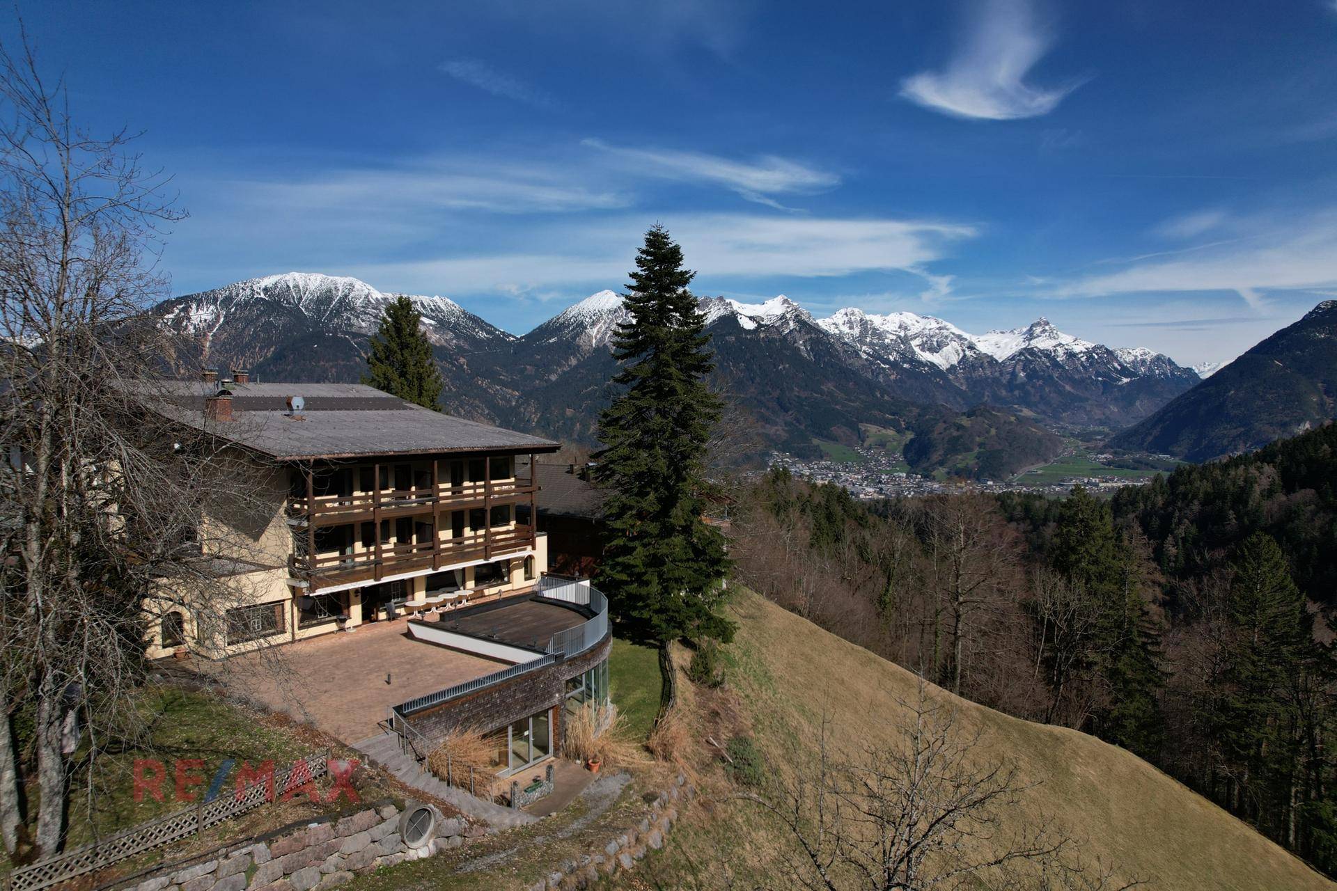 Panoramablick auf das Hotelgebäude mit seinen Balkonen und der umliegenden Berglandschaft unter blauem Himmel.