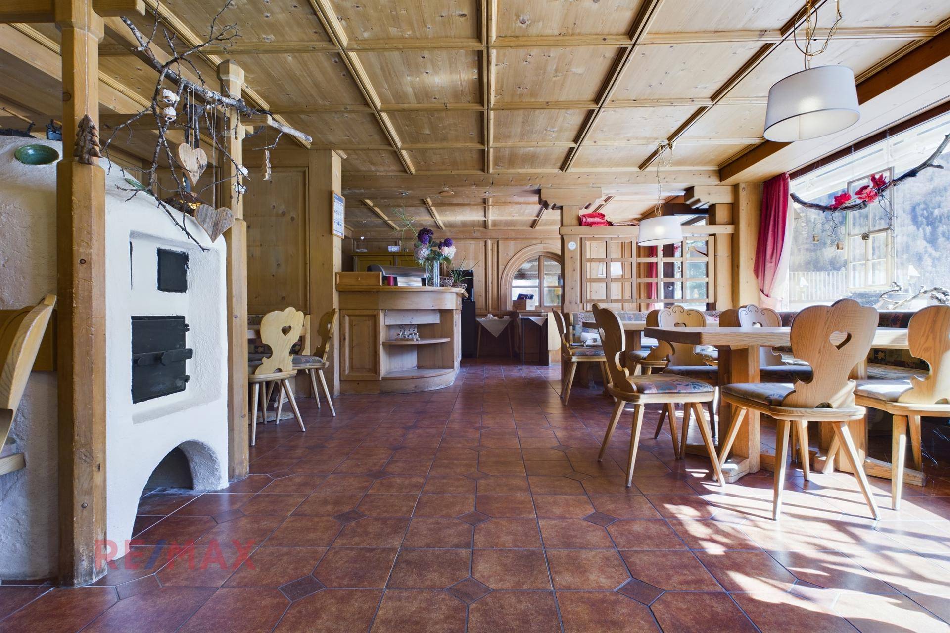 Gemütlicher Speisesaal im traditionellen Stil mit Holztäfelung, Kachelofen und rustikalen Möbeln.