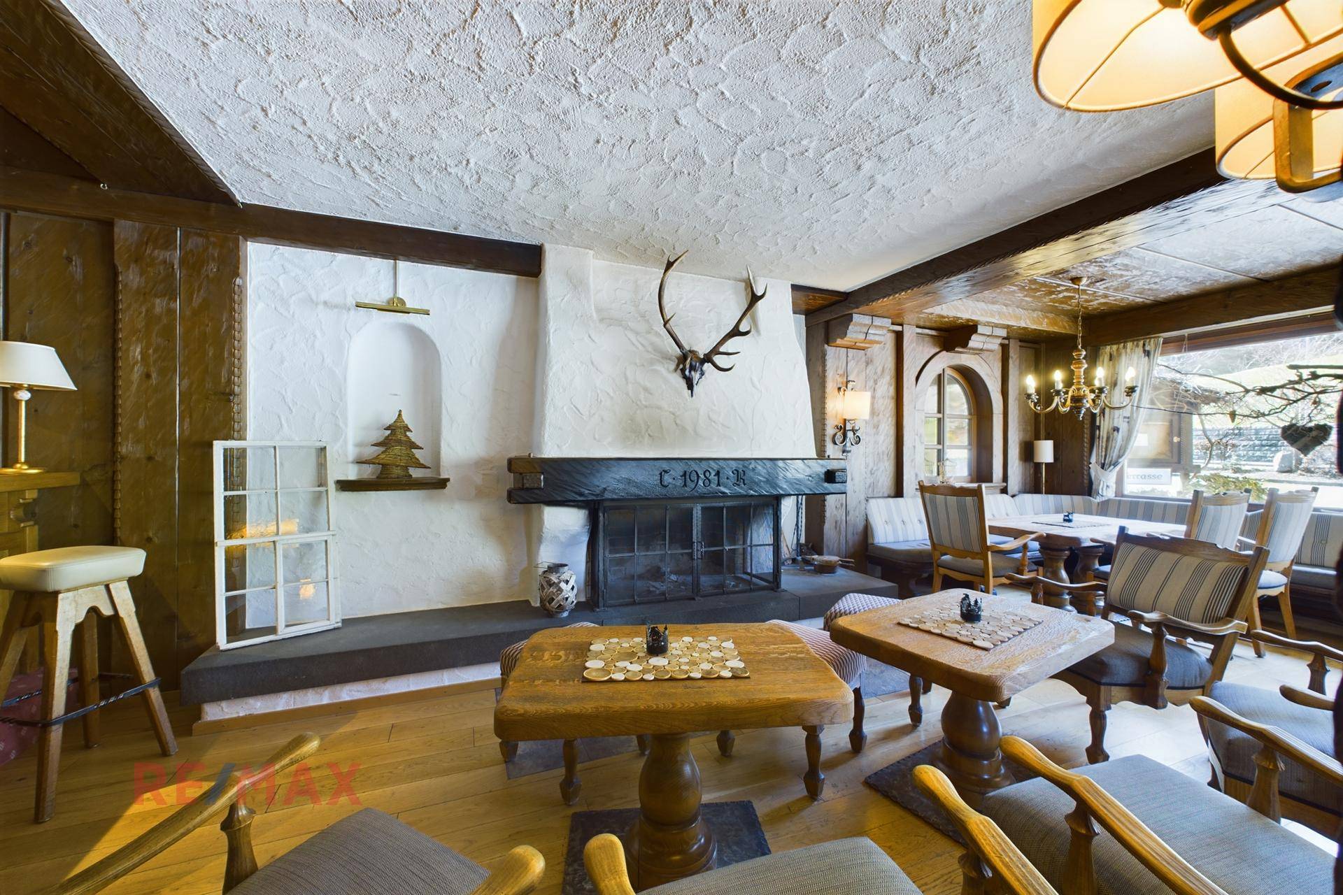 Traditioneller Loungebereich mit Kamin, rustikalen Holztischen und gemütlichen Sesseln, ideal zum Verweilen.