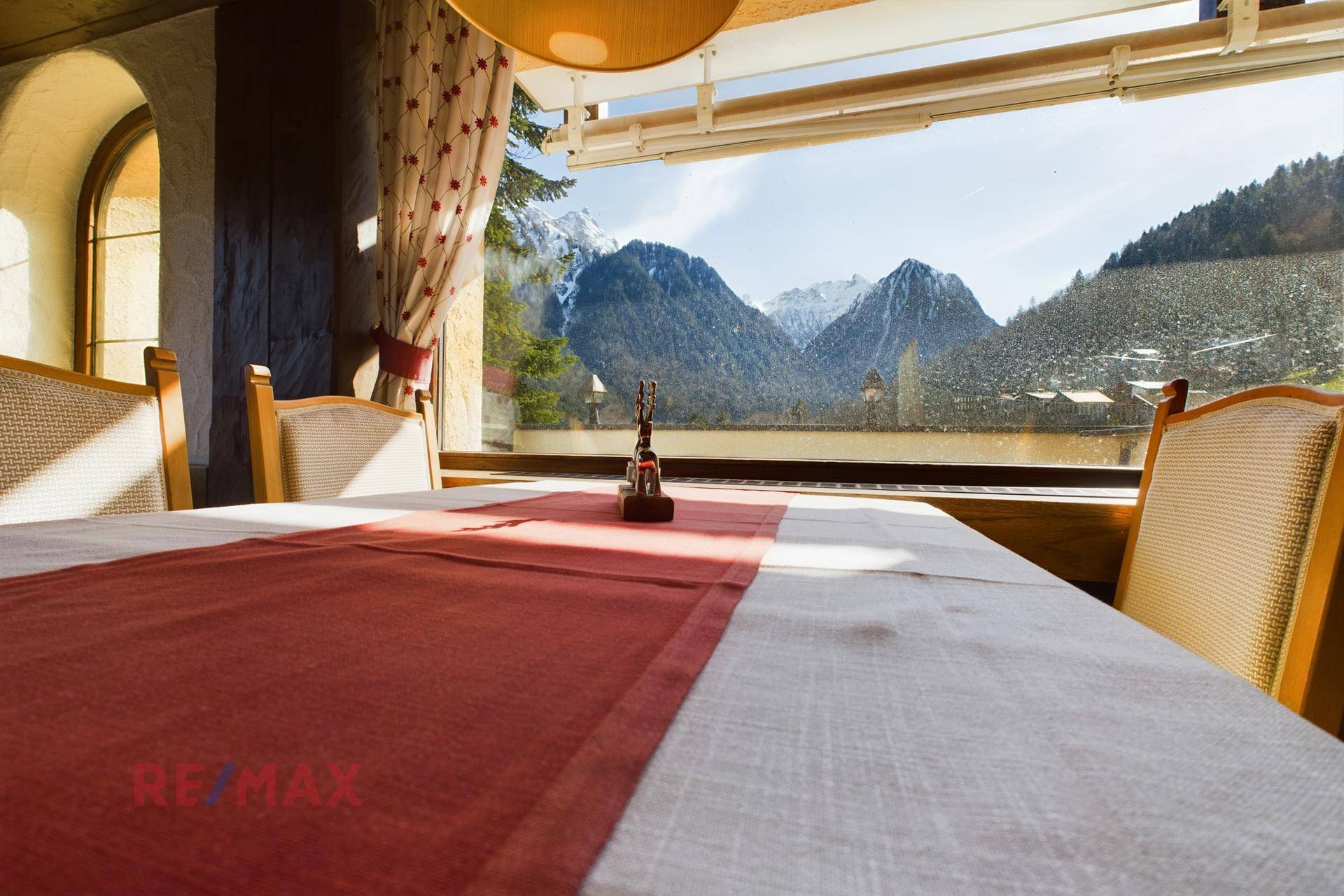 Essbereich mit Panoramablick auf die Berge durch ein großes Fenster, gedeckter Tisch für Gäste.