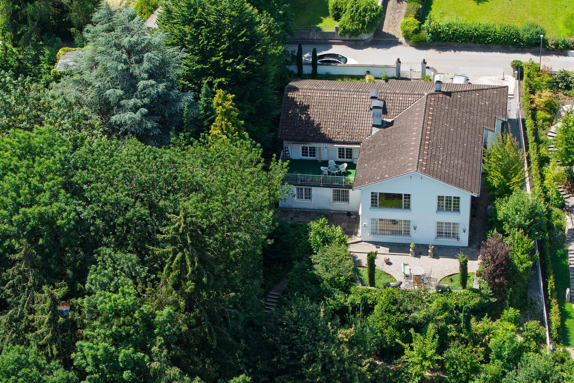Luftaufnahme eines Hauses mit gepflegtem Garten und einer möblierten Terrasse im Grünen.