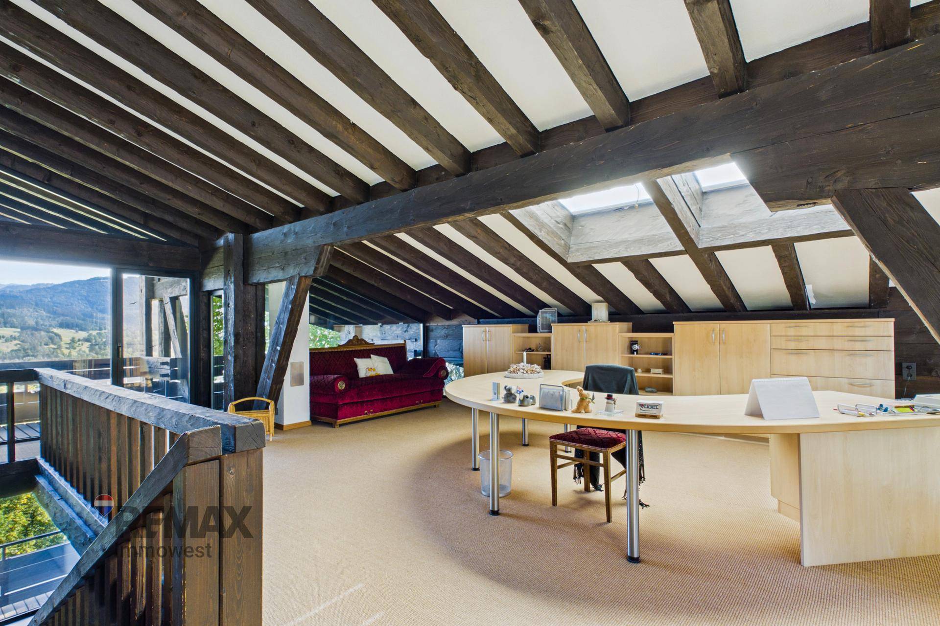 Geräumiges Büro im Dachgeschoss mit Schreibtisch, Stauraum und schrägen Decken mit Oberlichtern.