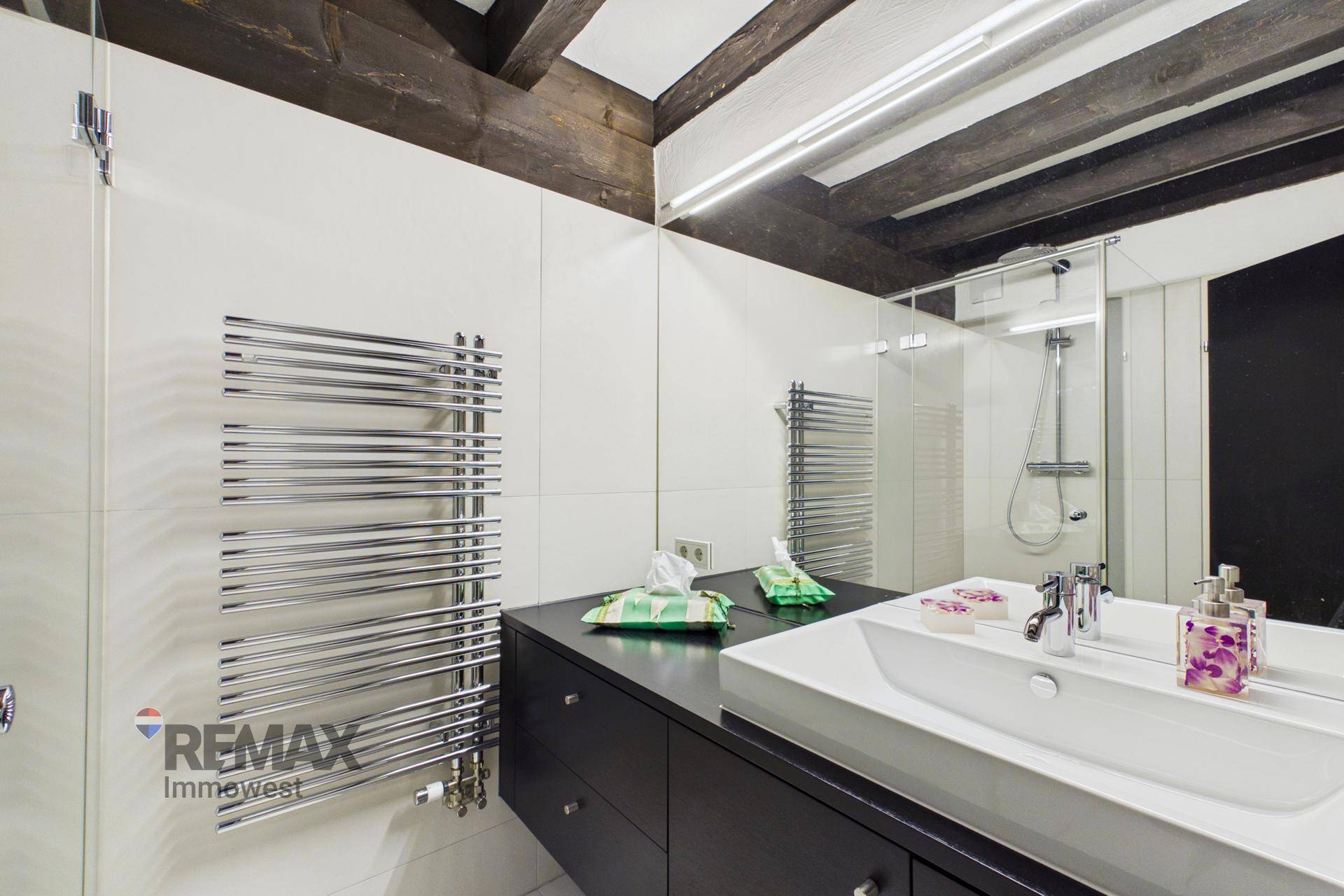 Badezimmer mit modernem Waschtisch, großem Spiegel und beheiztem Handtuchtrockner.