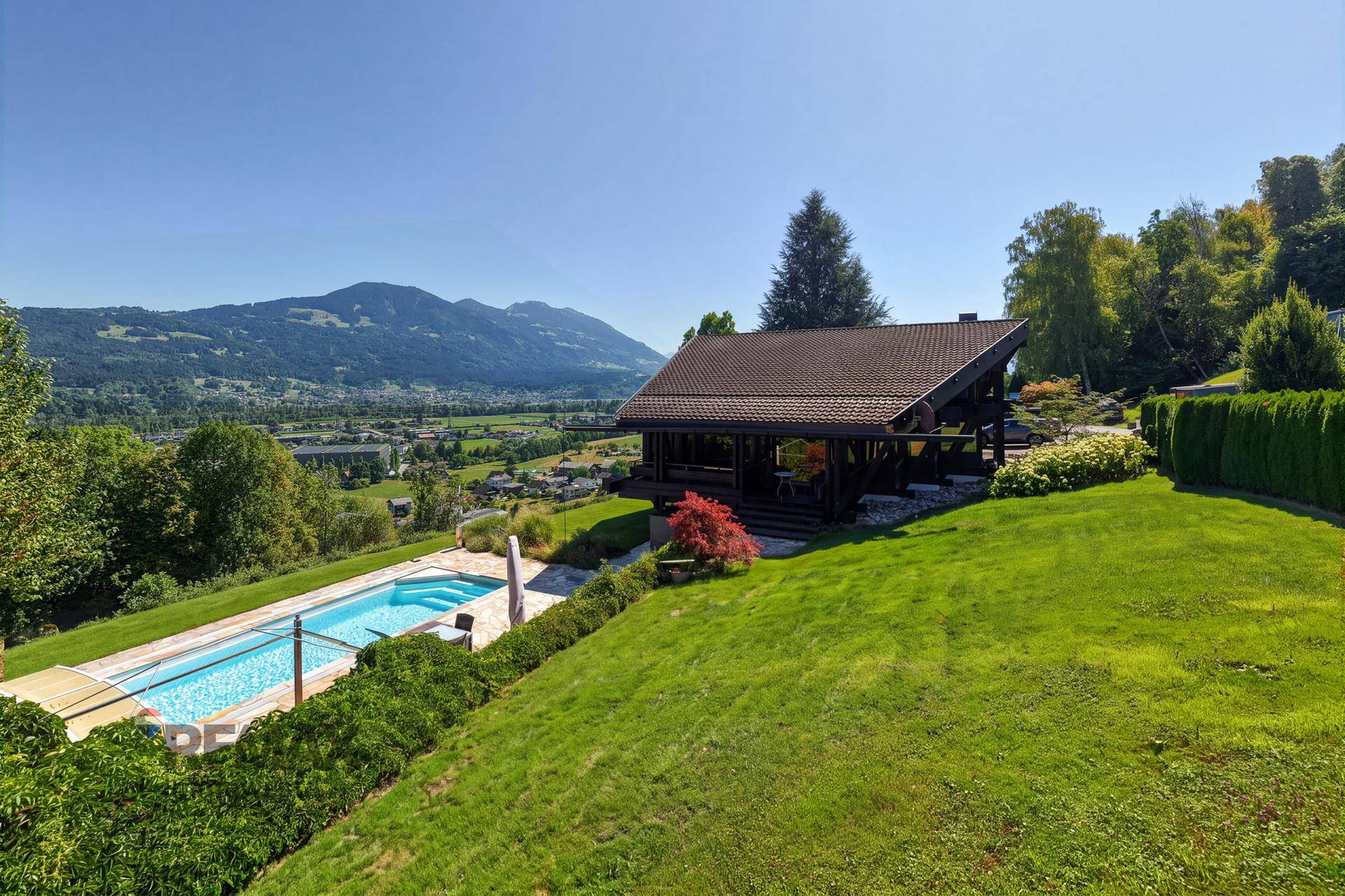 Charmantes Holzhaus mit Pool und weitläufigem Garten, eingebettet in eine malerische Berglandschaft.