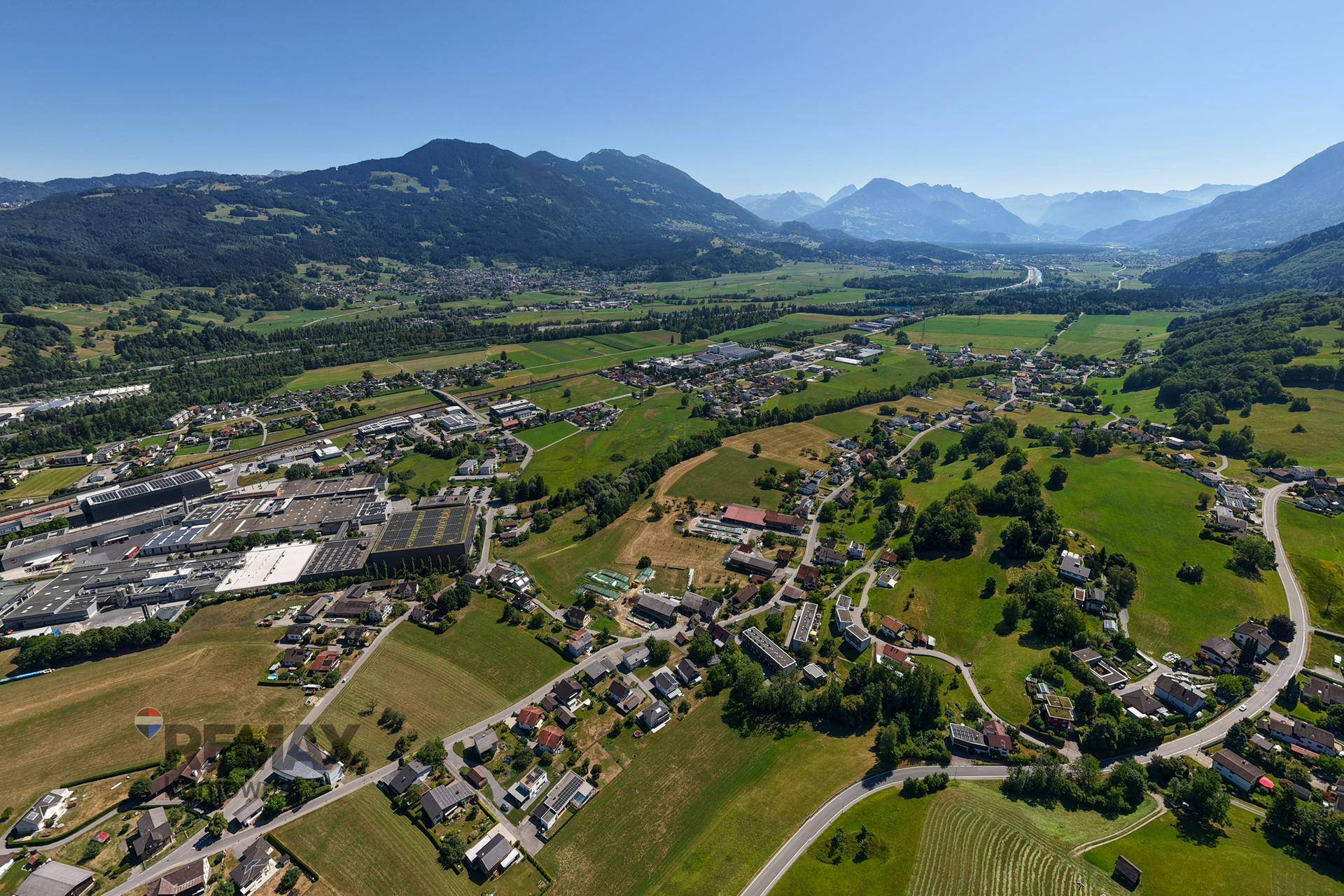 Weitläufige Luftaufnahme der ländlichen Umgebung mit Bergen, Tälern und kleinen Siedlungen.