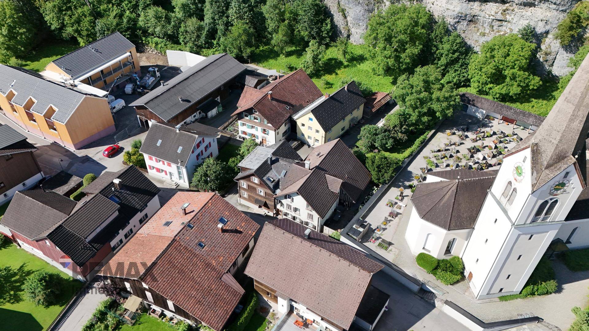 Luftaufnahme eines charmanten Dorfes mit Kirche und umliegender grüner Landschaft.