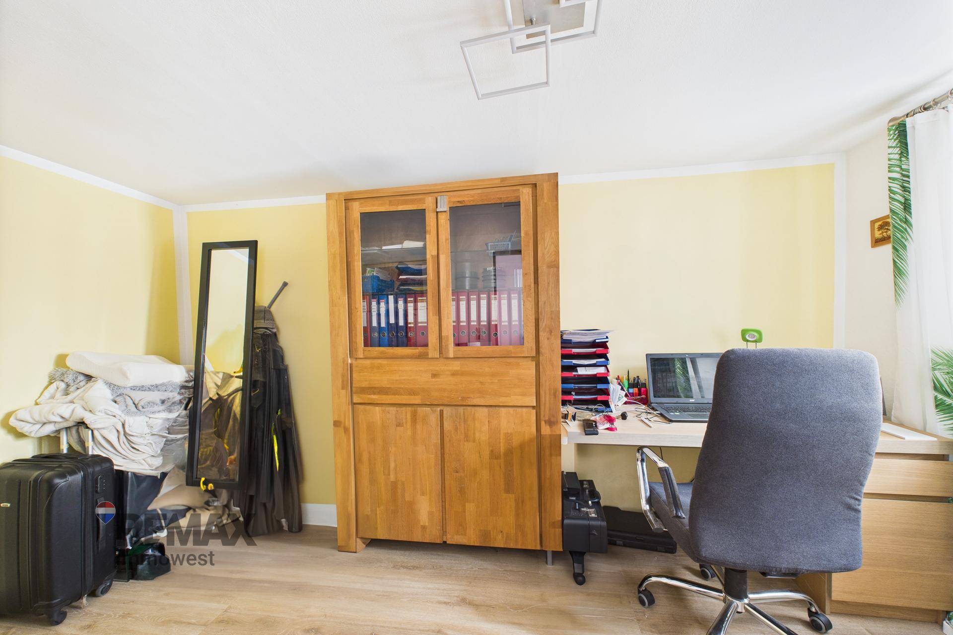 Funktionales Arbeitszimmer mit Holzschrank, Schreibtisch und gelben Wänden.