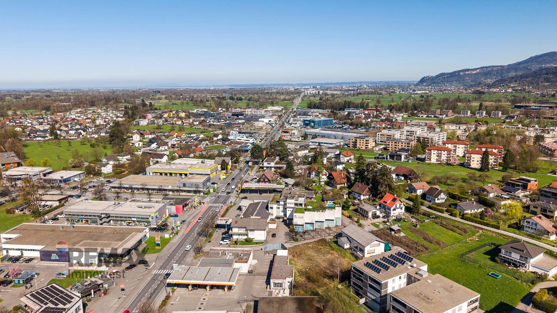 Luftaufnahme einer weitläufigen Siedlung mit Blick auf die Landschaft und einen See in der Ferne.