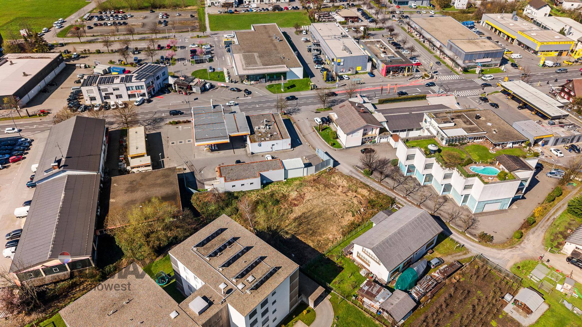 Detaillierte Luftaufnahme eines Baugrundstücks umgeben von verschiedenen Gewerbebetrieben und Parkplätzen.