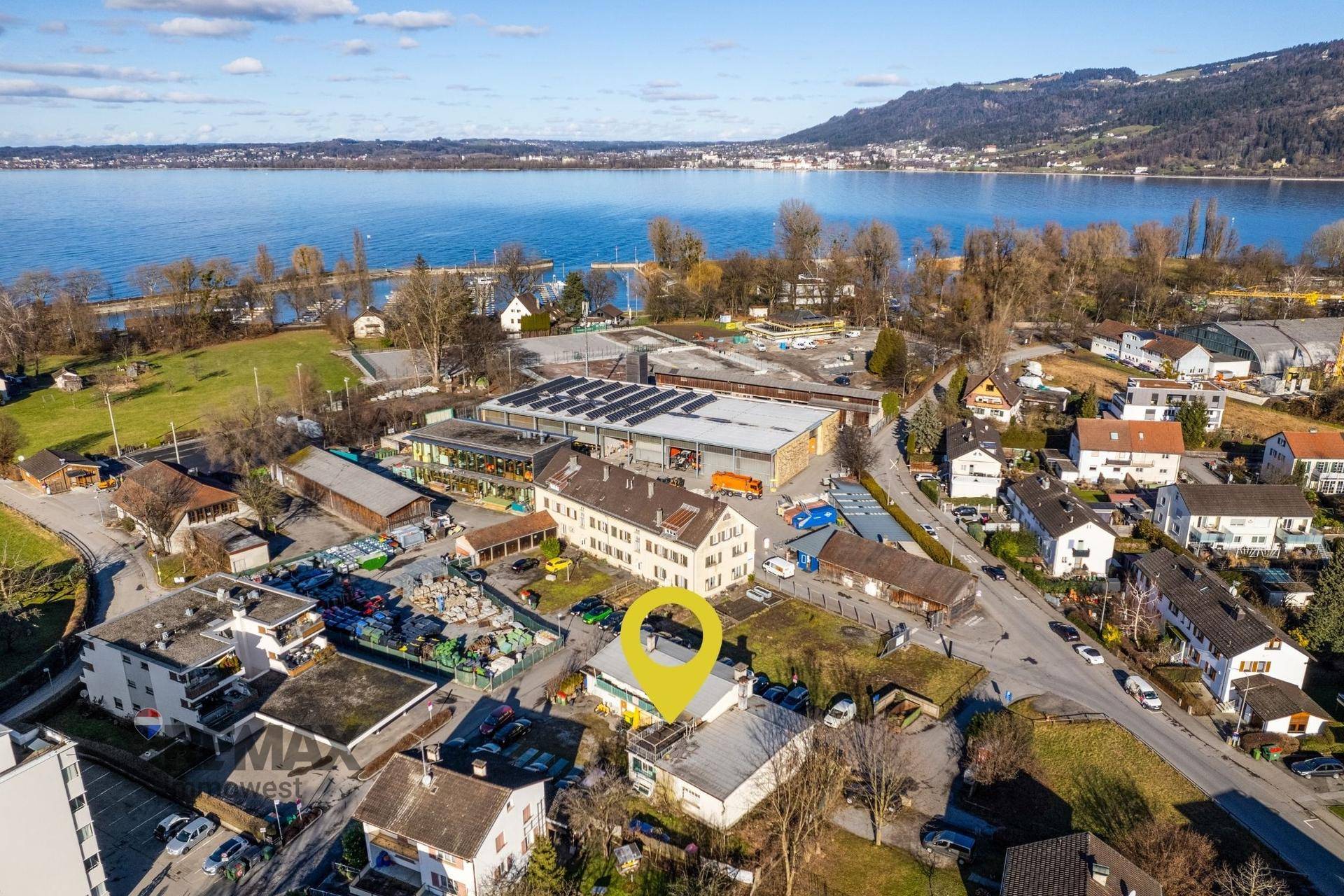 Luftaufnahme des Standorts mit Markierung, umgeben von Wohngebäuden und einem See im Hintergrund.