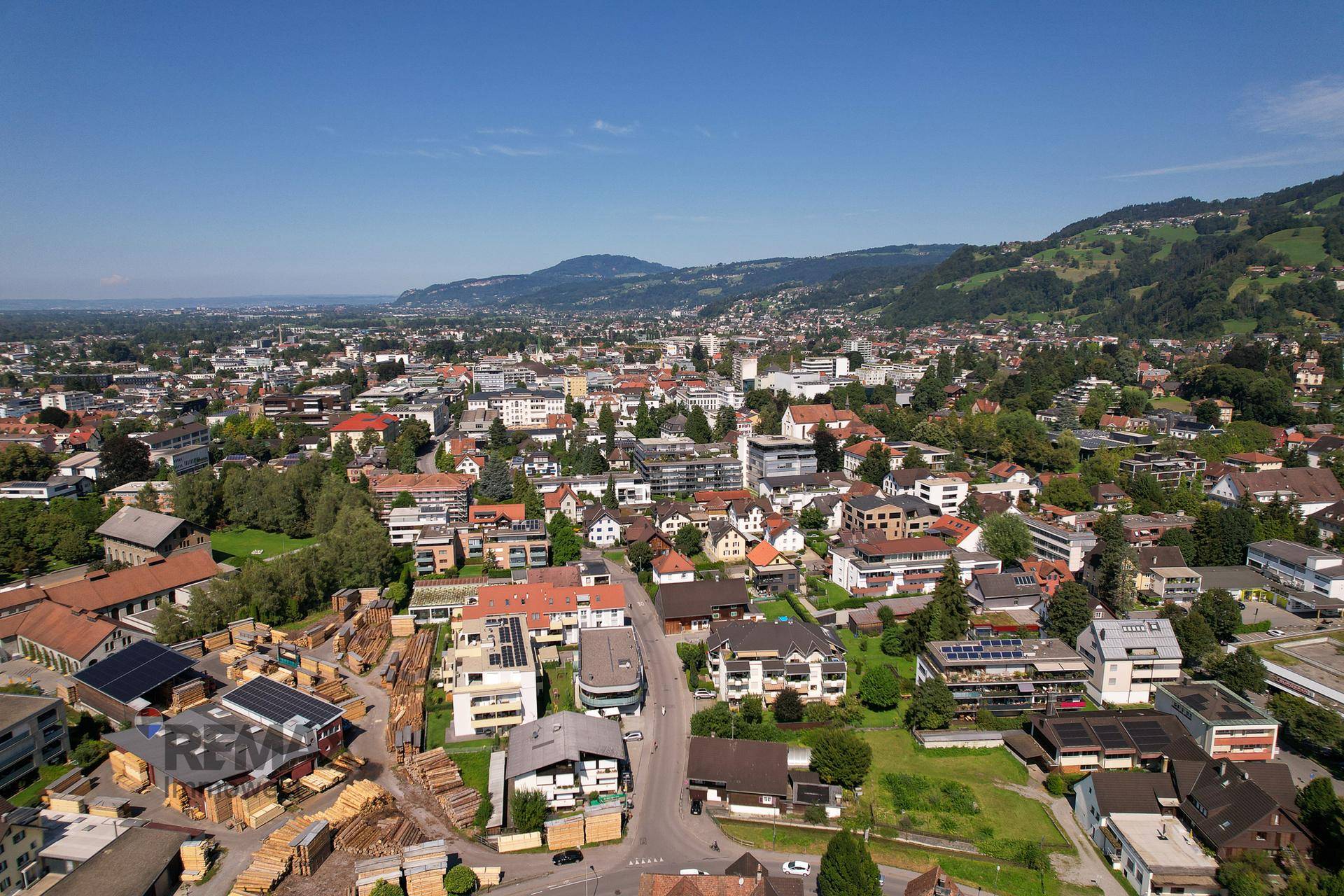 Panoramablick aus der Vogelperspektive auf eine Stadtlandschaft mit vielen Häusern und Bergen am Horizont.