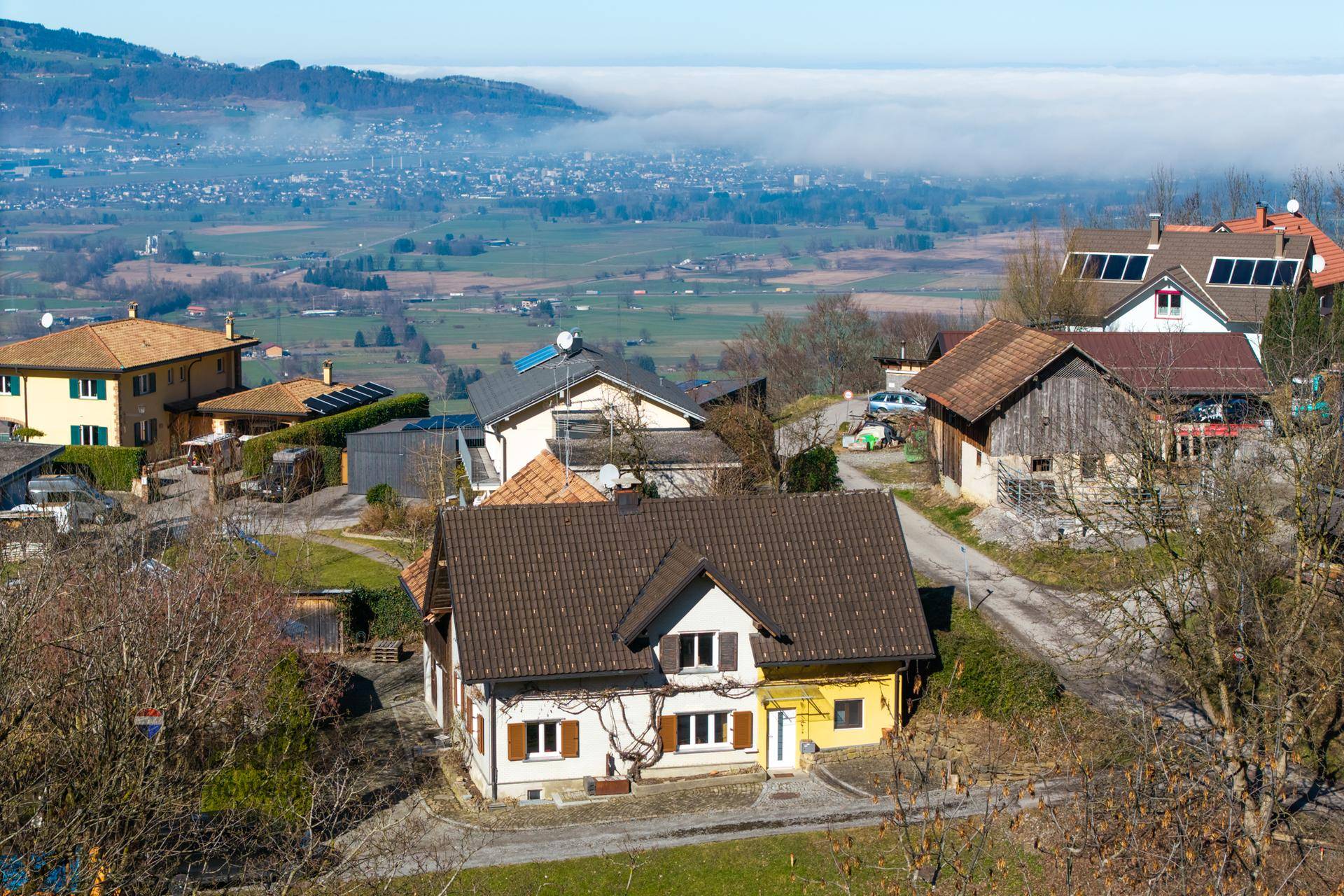 Haus in ländlicher Umgebung mit Blick auf ein nebliges Tal und die umliegende Hügellandschaft.