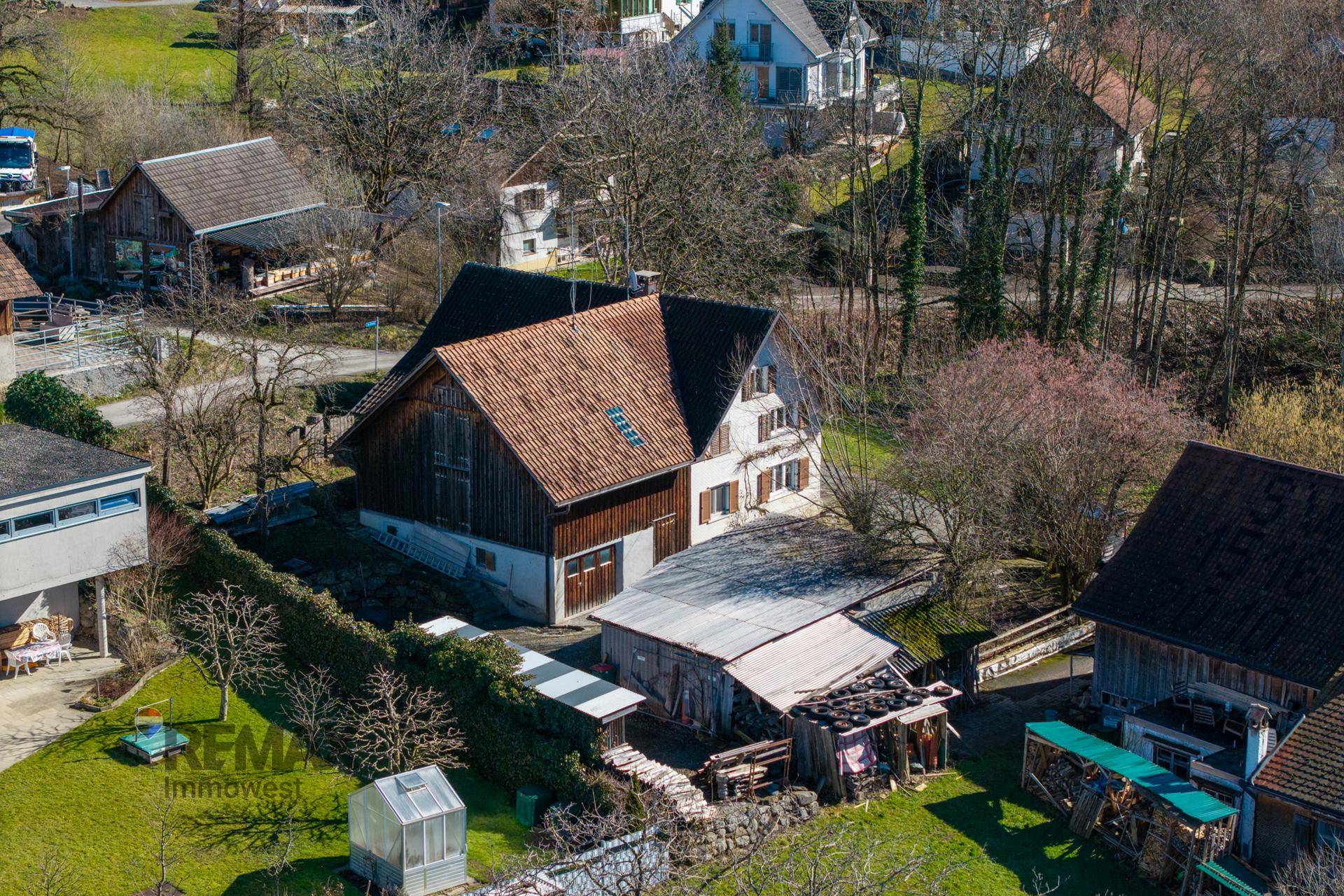 Vogelperspektive eines traditionellen Hauses mit angrenzendem Schuppen und Gartenbereich in sonniger Lage.