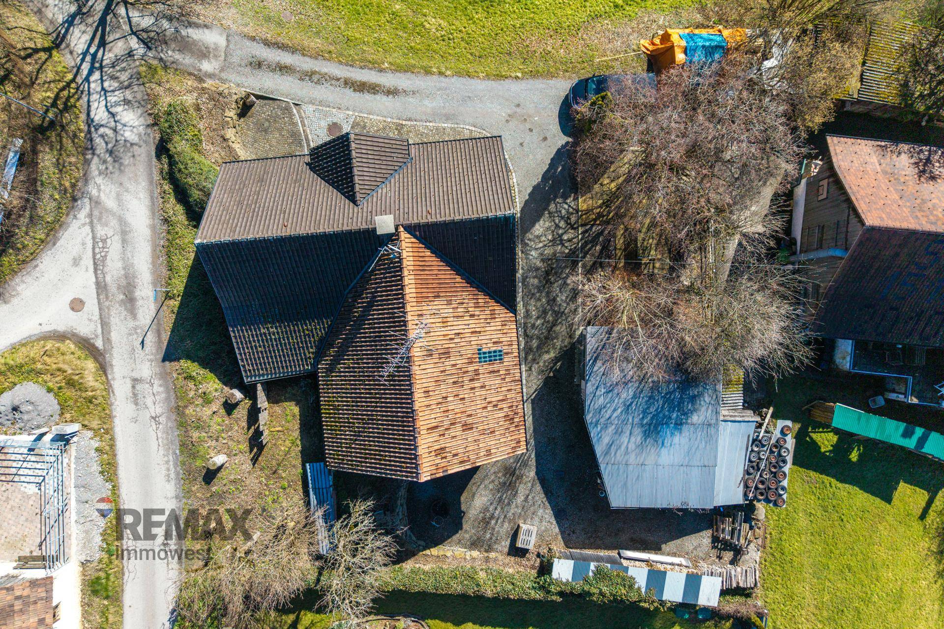 Direkte Draufsicht auf das Haus mit seinen Dächern und dem umliegenden Grundstück.